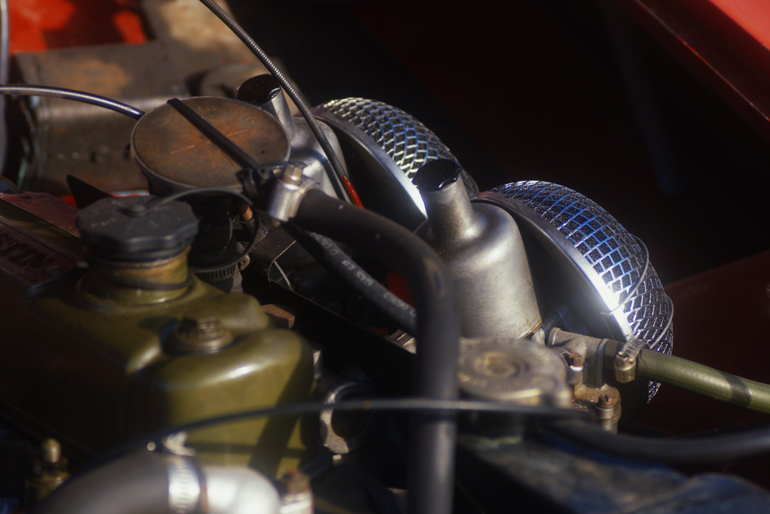 Close-up of a motorcycle engine with various metallic and black parts, including air filters with a mesh design.