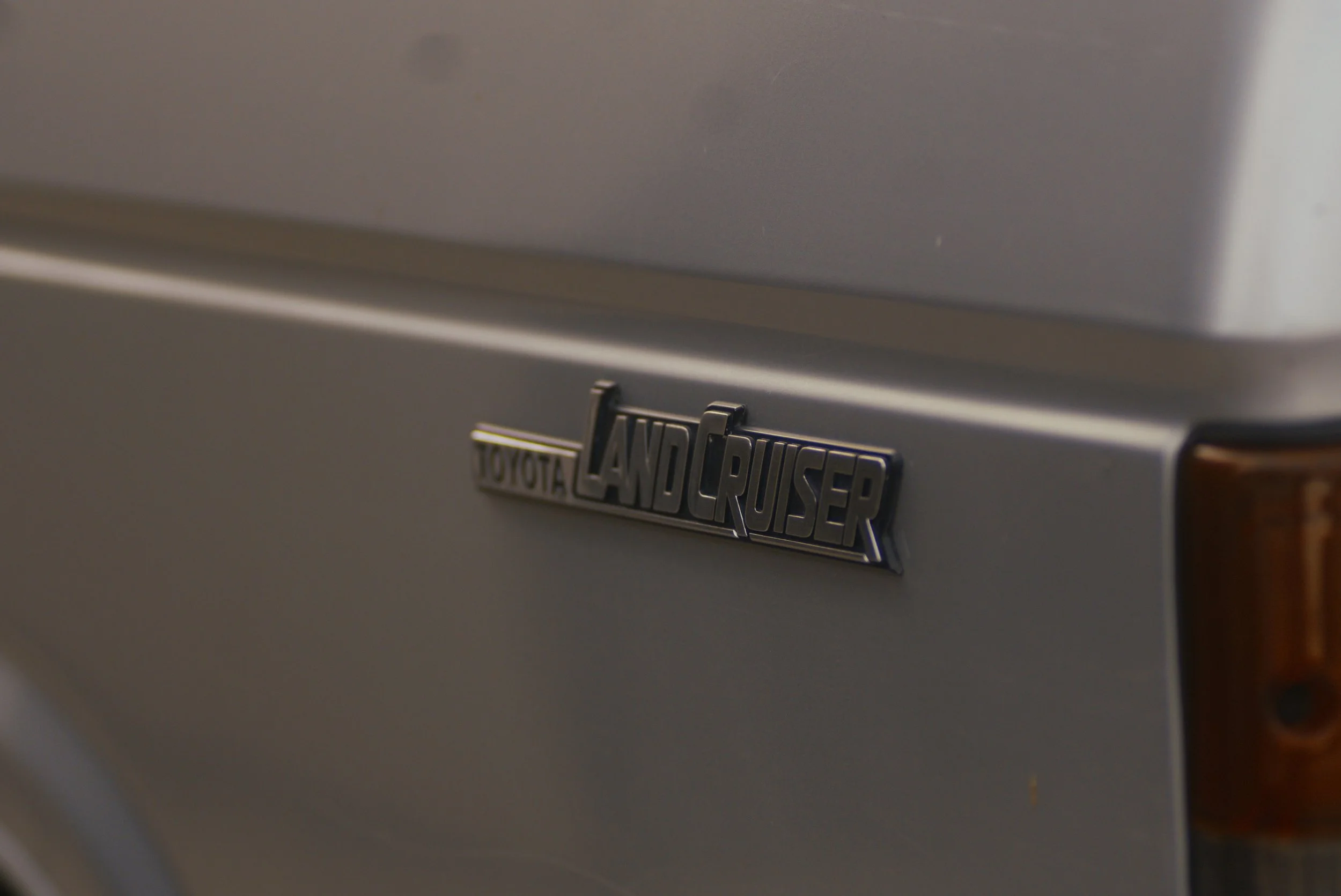 Close-up of a silver Toyota Land Cruiser emblem on a vehicle's back.