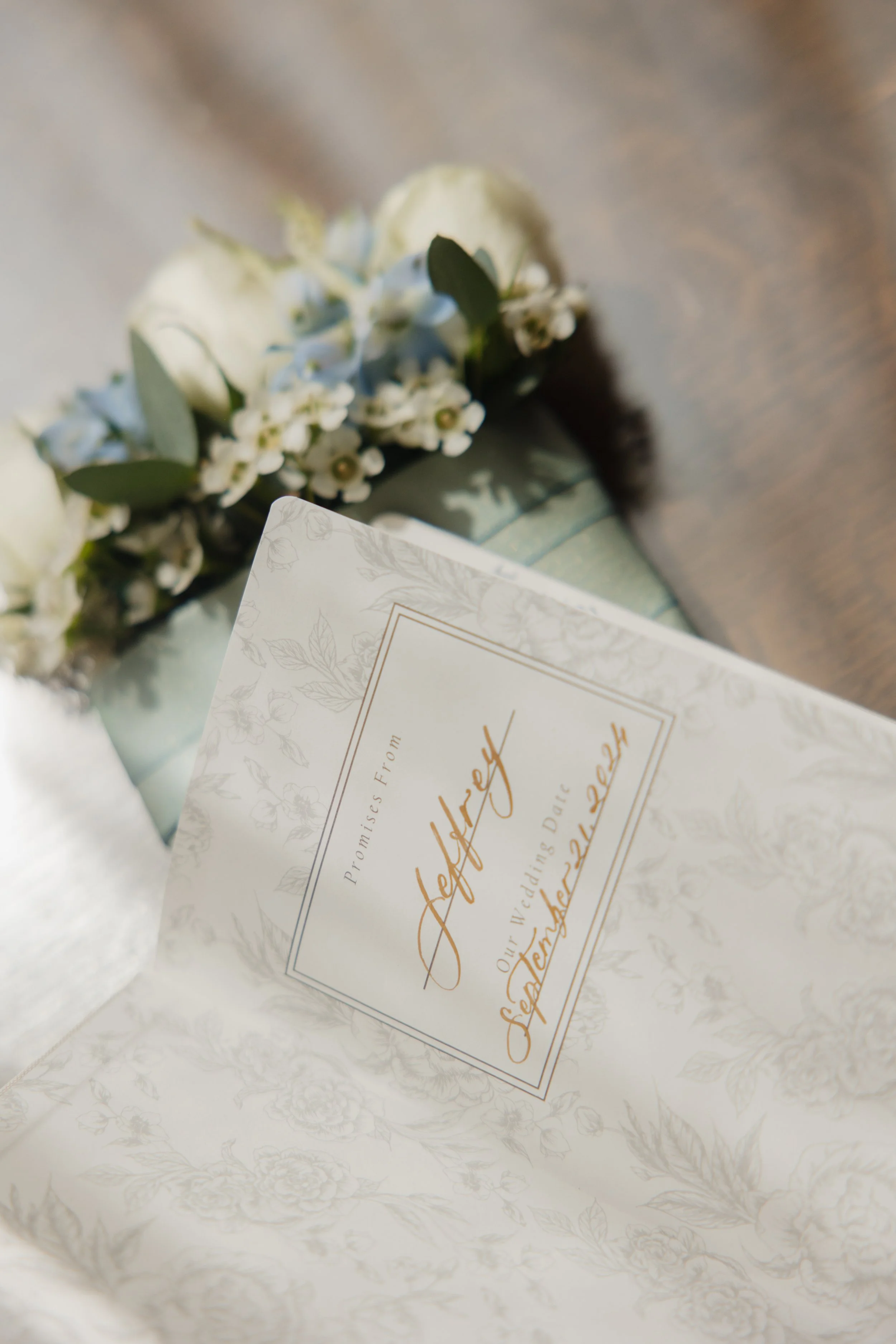Invitation card with floral design and a bouquet of white and light blue flowers. The card overlay partially displays text in cursive, including the words 'Left' and 'September'.