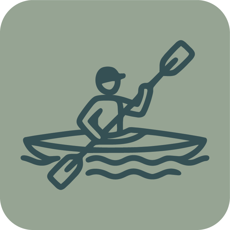 A person kayaking on water, holding a paddle, wearing a cap and smiling.