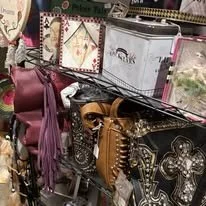 A display of handbags with various patterns and embellishments, including some with metallic and floral designs, on a store shelf.
