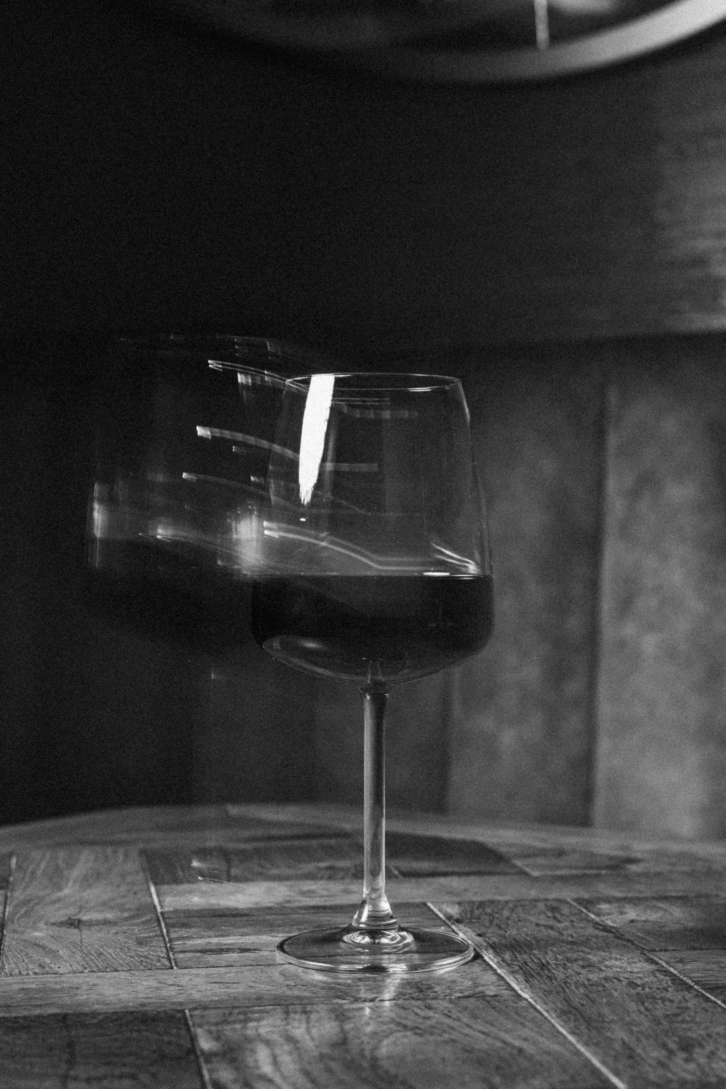 Una copa de vino sobre una mesa de madera, en un ambiente oscuro y elegante.