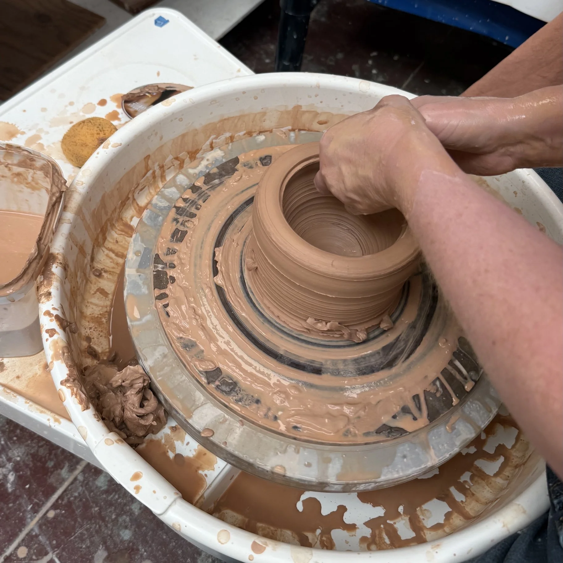 hands throwing a pot on the pottery wheel