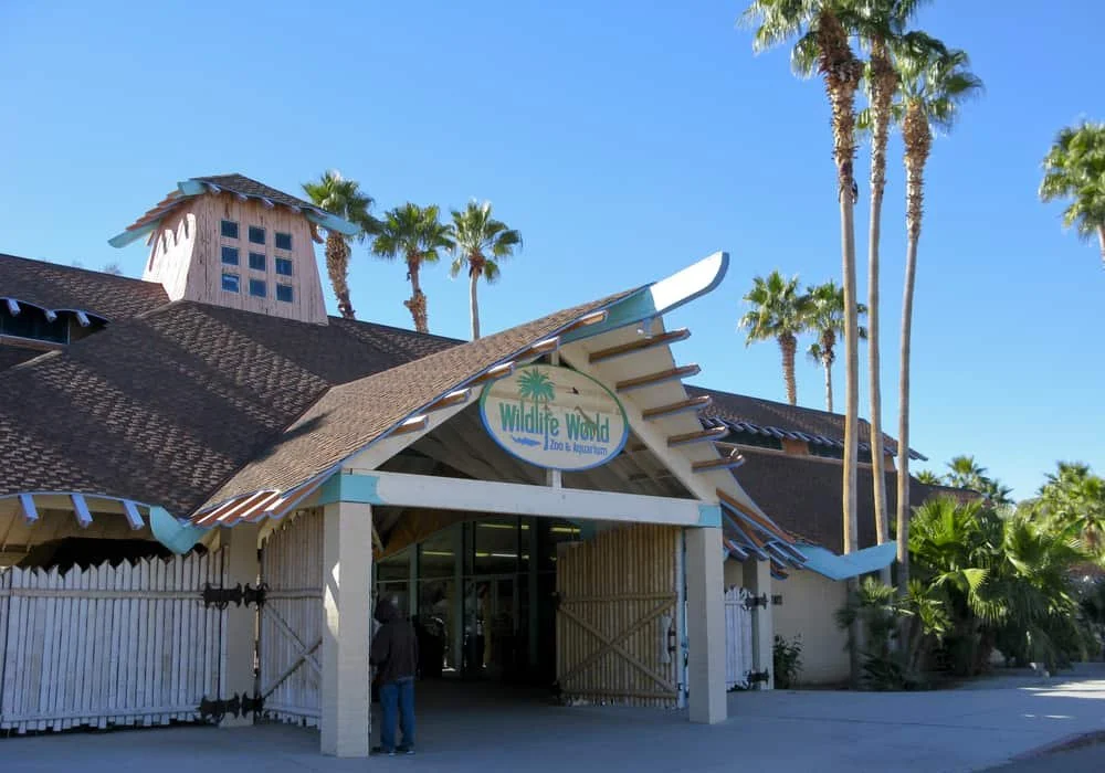 Wildlife World Zoo and Aquarium entrance with palm trees and blue sky.