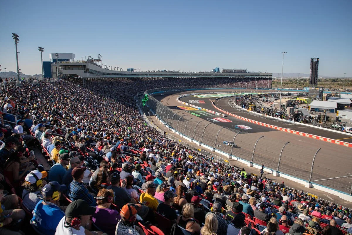 Crowd at a NASCAR race at a race track in a desert area.