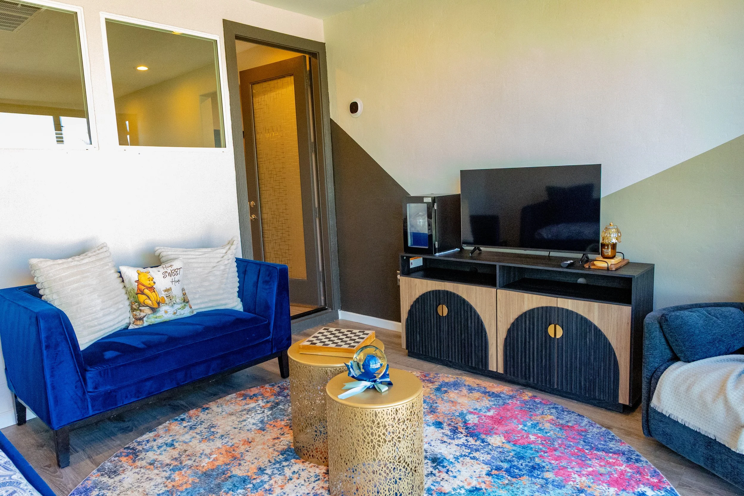 A living room with a flipped couch, wall art, a TV on a stand, and a door leading to another room.