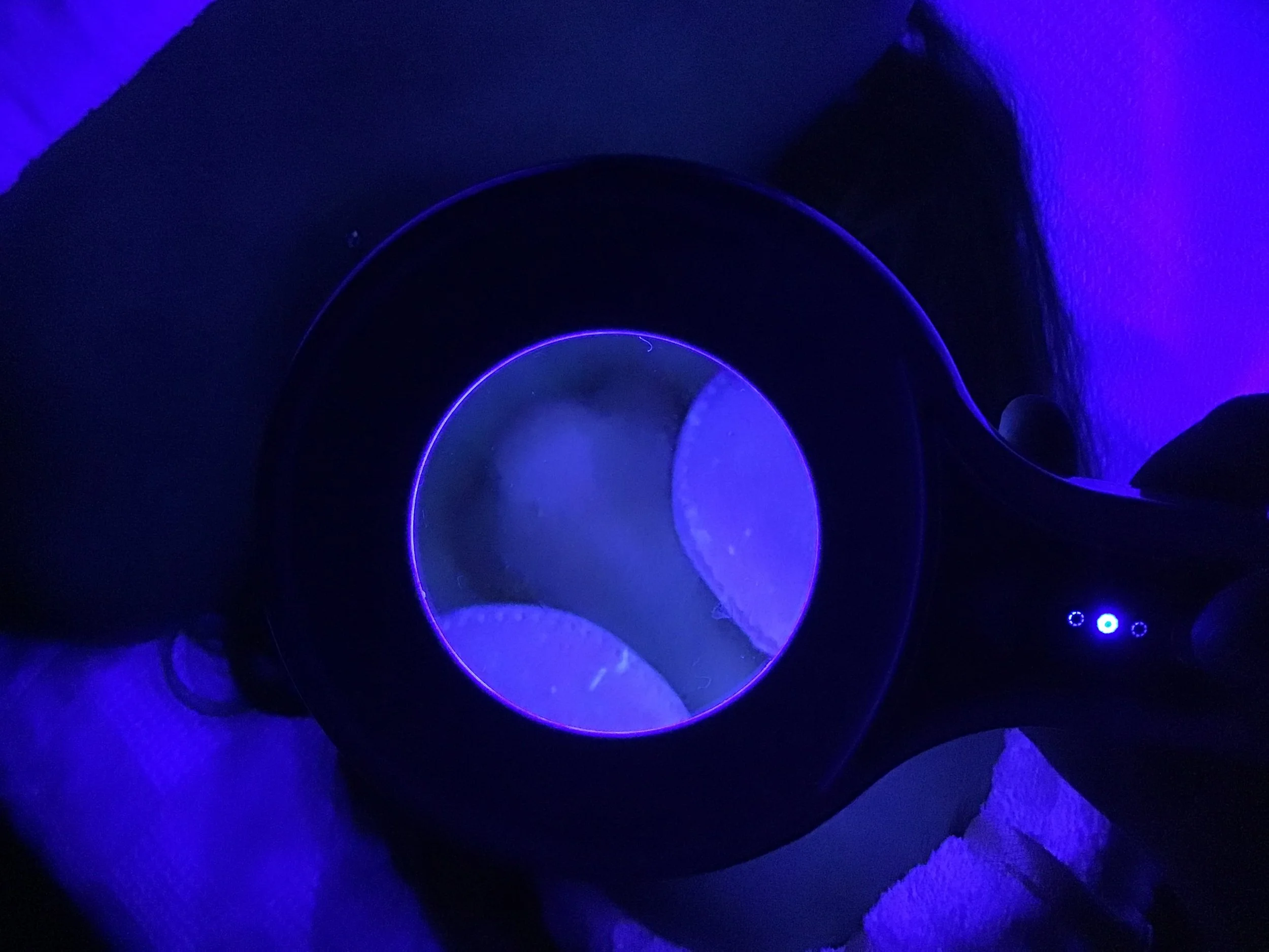A spiral object illuminated with blue and purple neon lights in a dark setting.