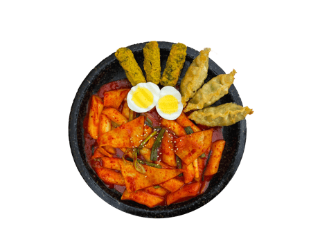A black bowl filled with spicy gochujang rice cakes, fried fish, boiled eggs, and pickled vegetables.