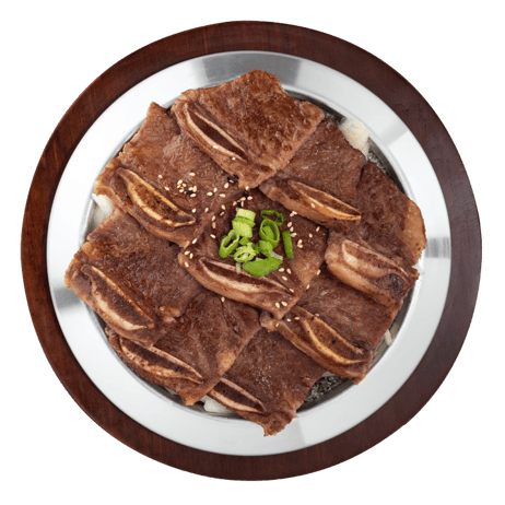 A plate of cooked pork belly slices garnished with chopped green onions and sesame seeds.