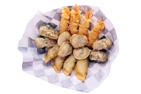 Assorted fried foods including shrimp tempura, chicken nuggets, and fried mushrooms on checkered paper.
