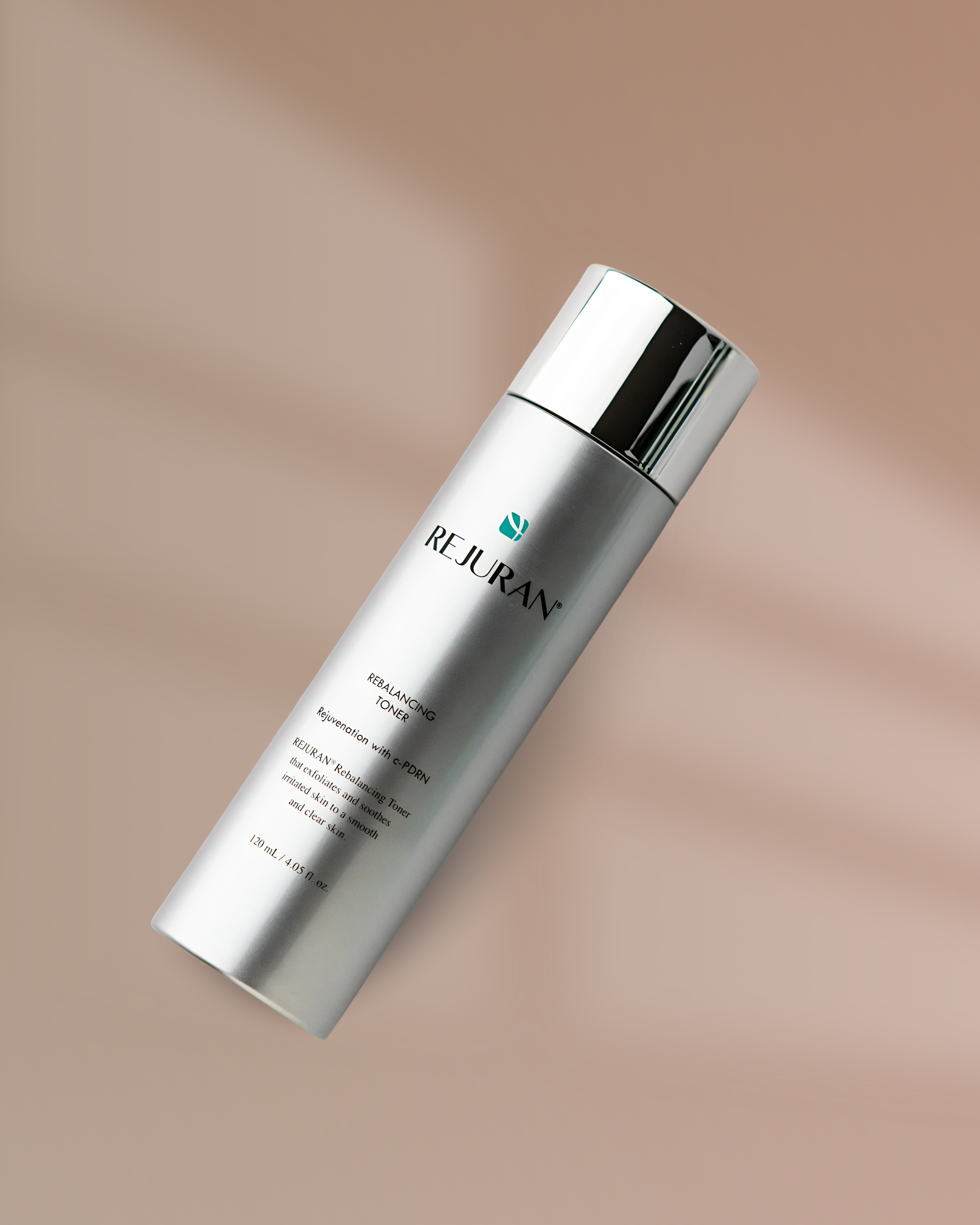 A silver cylindrical bottle with a shiny cap, labeled 'Rejuran' and 'Rebalancing Toner,' resting on a beige surface. The bottle's label describes the product as a toner for skin rejuvenation.