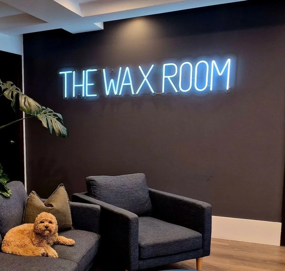 The Wax Room waiting area with neon The Wax Room sign on the wall.