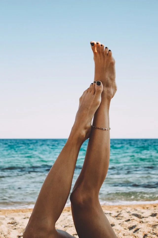 Smooth legs in the air with the ocean in the background.