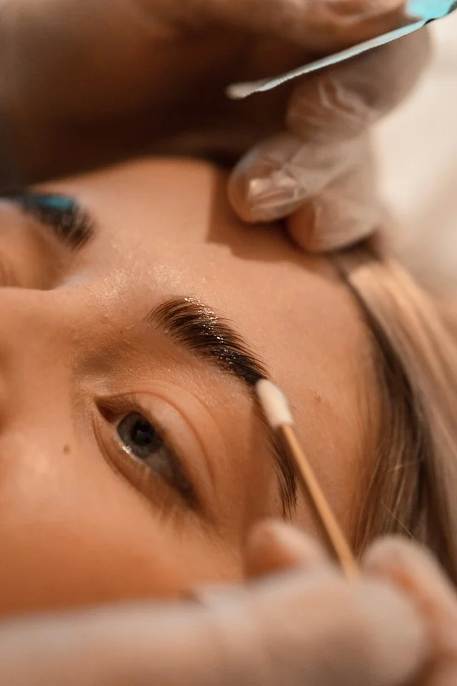 A cotton bud being used to smooth brow hairs into place.