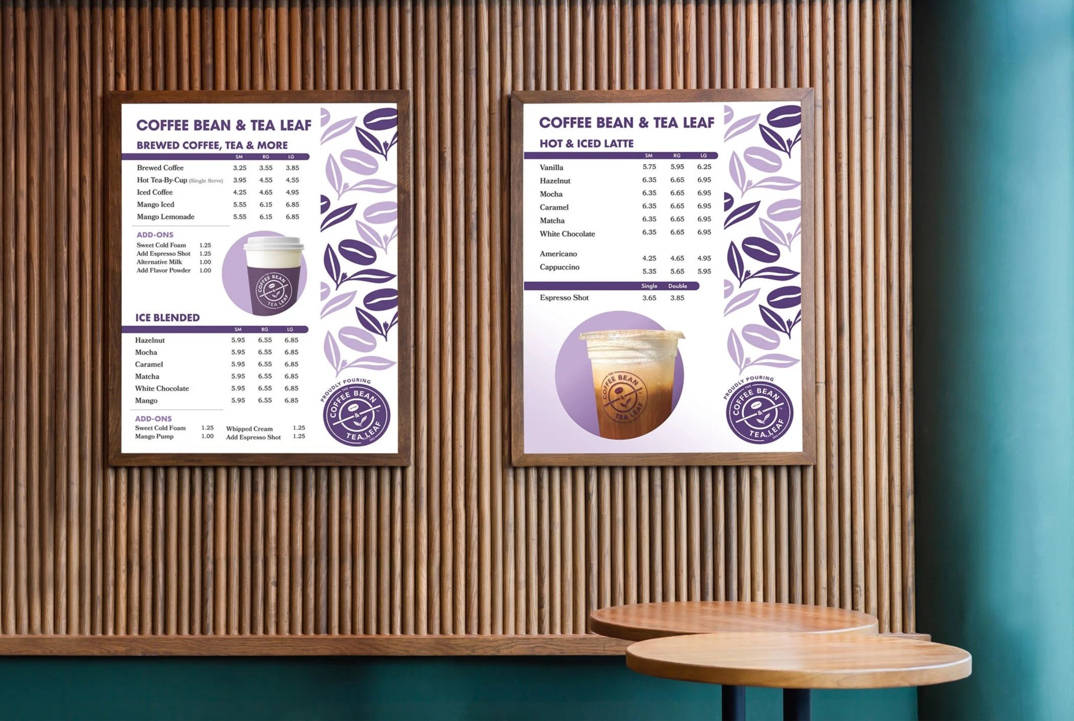 Two menu boards display various coffee and tea drinks on a wooden wall, with small round wooden tables in front.