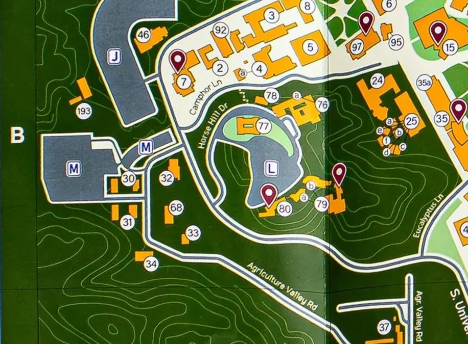 Map of a university campus with buildings, roads, and points of interest marked with numbered and lettered labels, showing garden and forest areas.