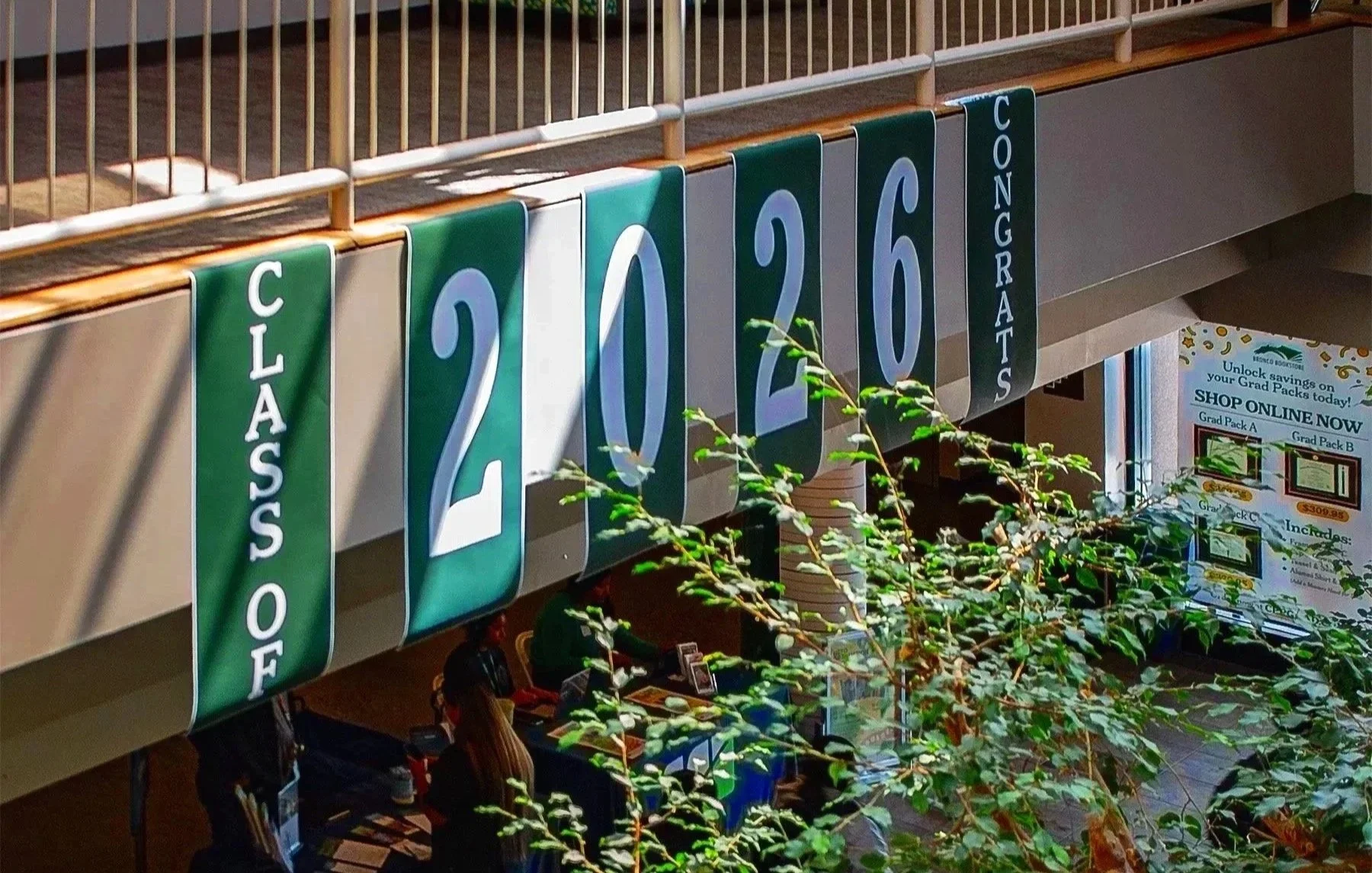Vertical banners displaying the date 'August 26, 2020' and the word 'Congratulations' in an indoor setting with a railing at the top and some green plants partially obscuring the view.