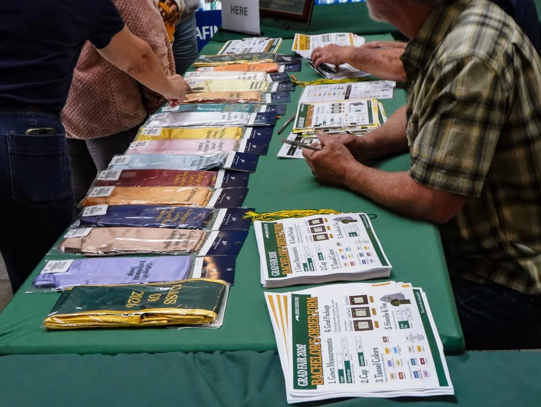 Display table with graduation cords, brochures, and informational flyers at a graduation event.