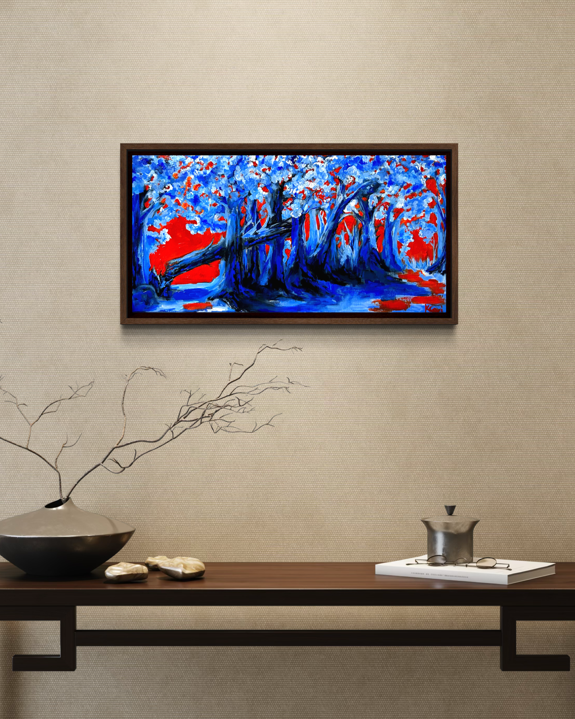 A wall art painting of a blue and red abstract landscape hung above a wooden console table. Bright blue trees contemporary.