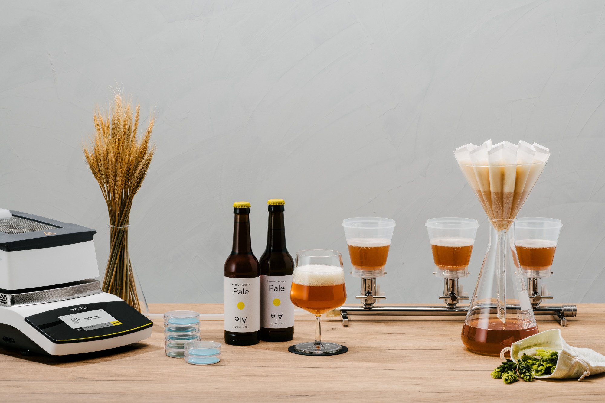 Mostrador de bar con botellas, vasos con cerveza, máquina de cerveza, frascos y decoraciones con trigo y flores.
