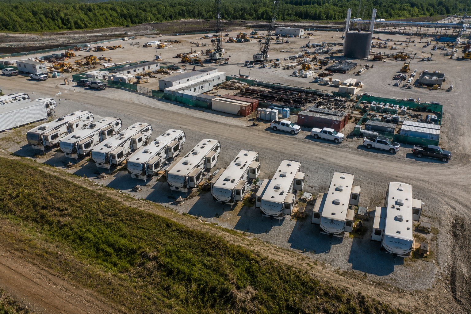 Aerial view of fully furnished fifth-wheel RVs providing temporary workforce housing beside an active industrial construction site.