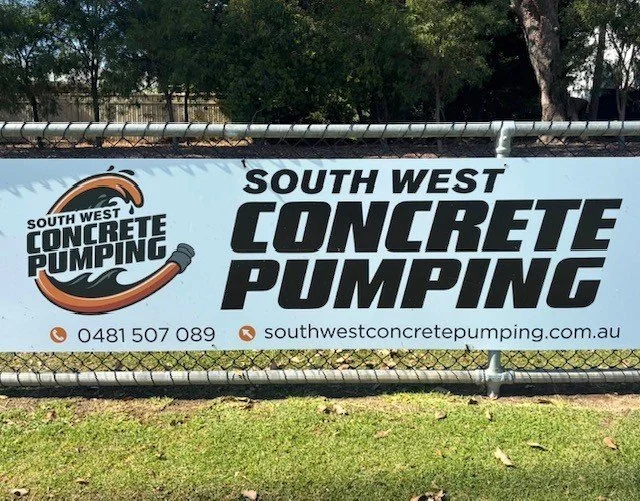 Banner for South West Concrete Pumping on a chain-link fence with phone number and website, featuring a logo with a concrete pipe and splash.