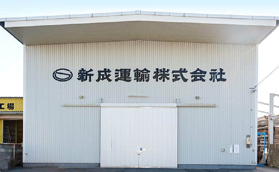 白い工場の外壁に黒字で会社名が書かれている