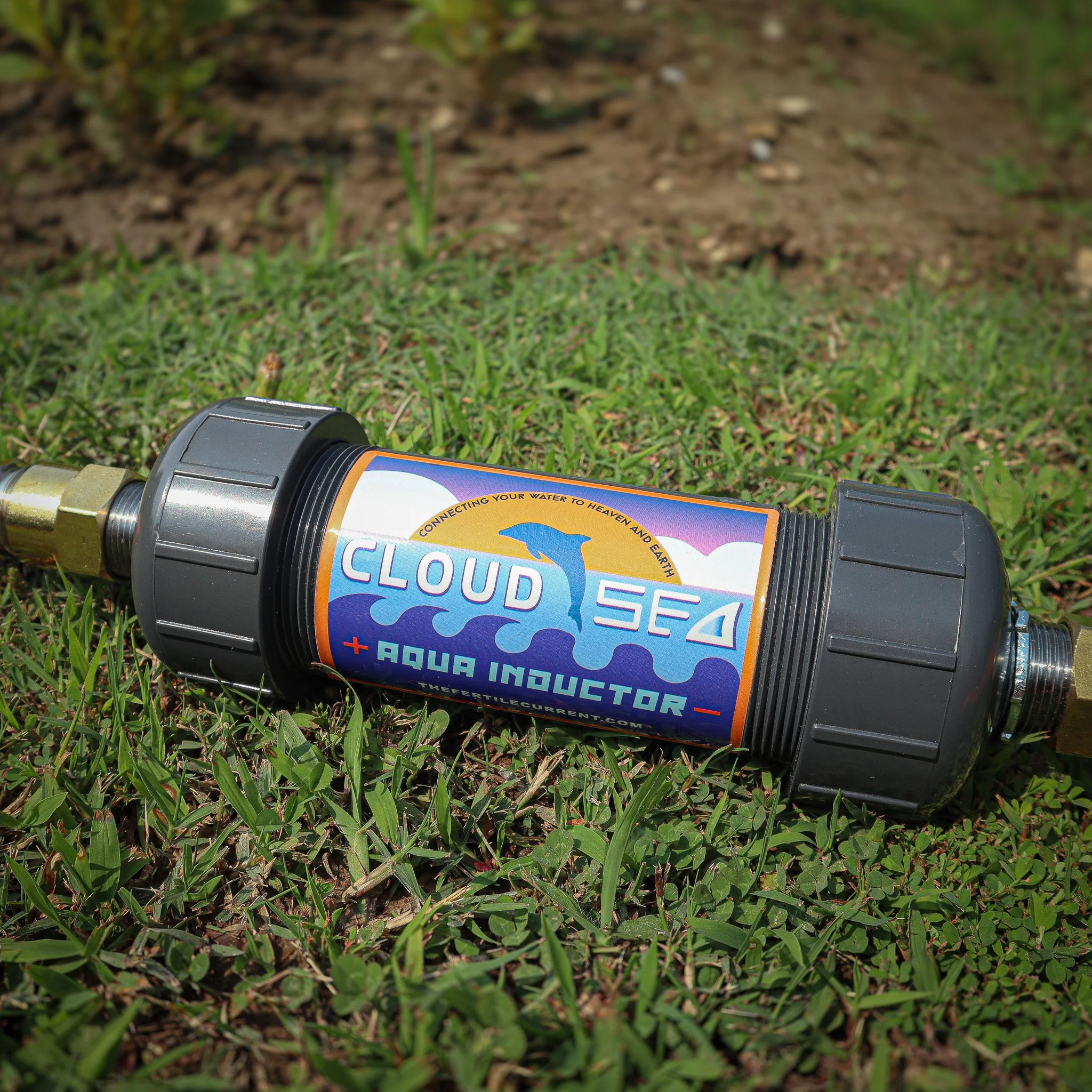 A water flow restrictor device lying on grass and soil, with colorful labels about water conservation and aquarium use.