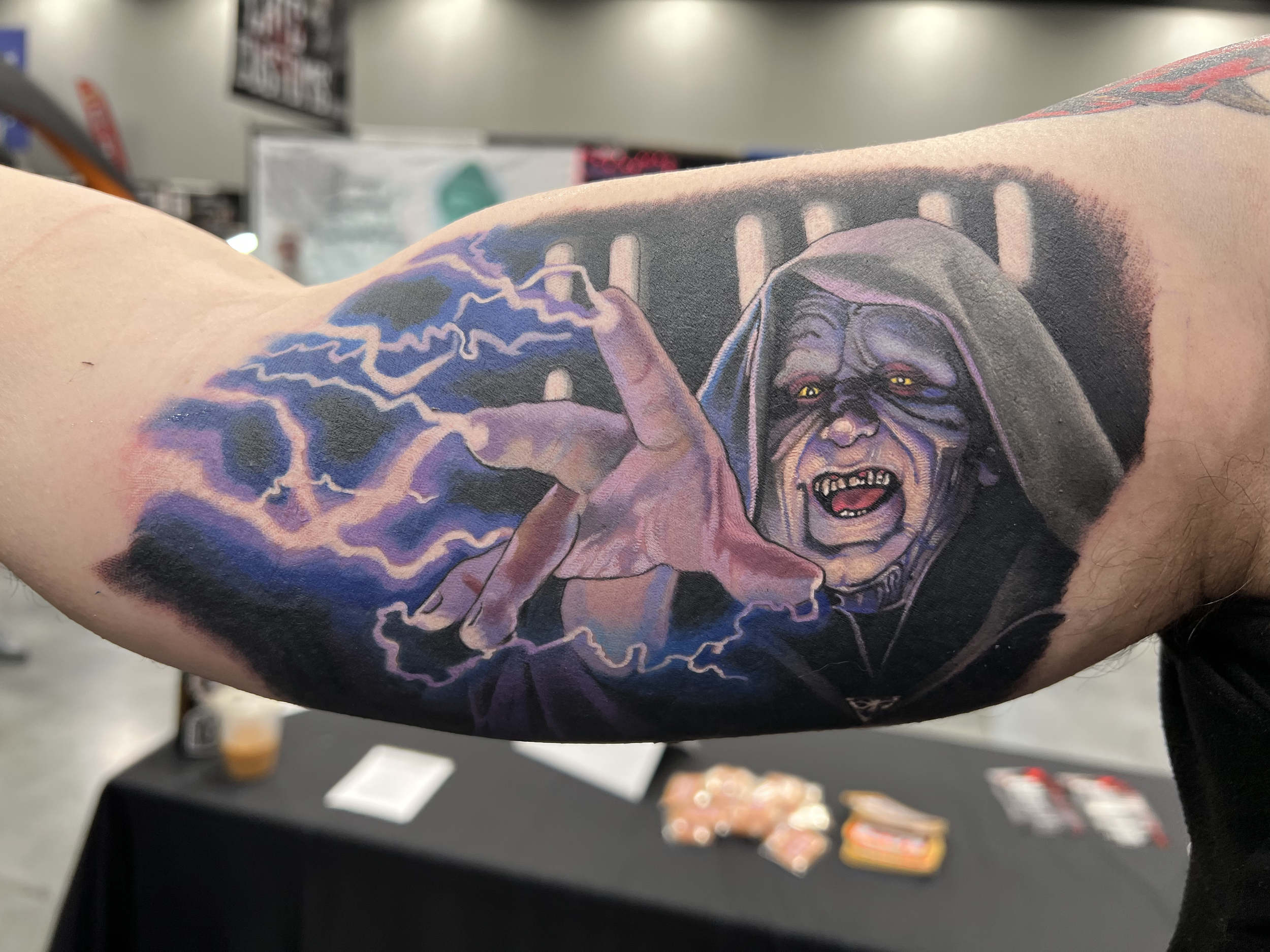 Tattoo of a witch with glowing yellow eyes, wearing a hood, with lightning and storm clouds in the background.