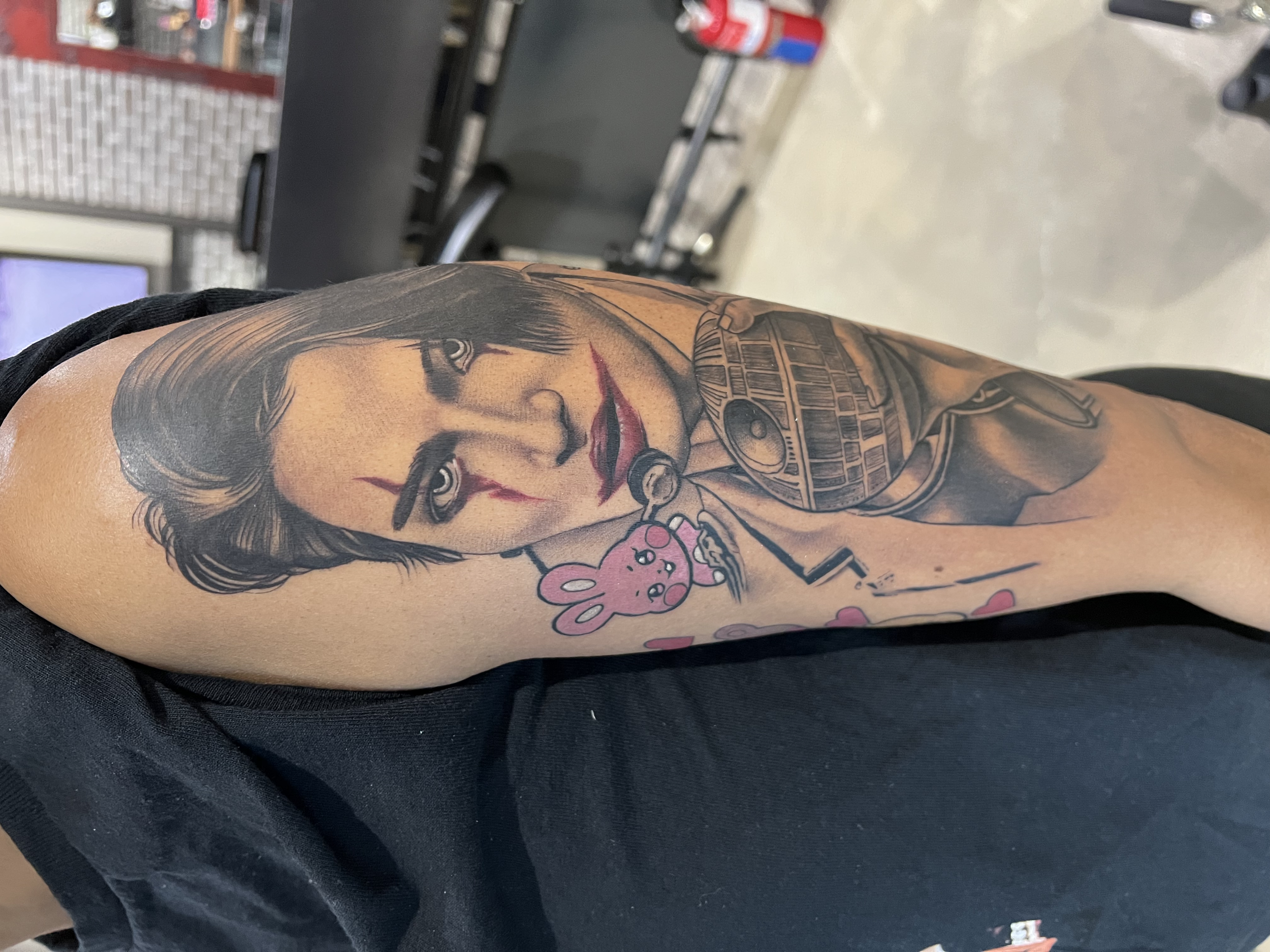 A person's arm with a detailed tattoo of a woman's face and a pink bunny illustration.