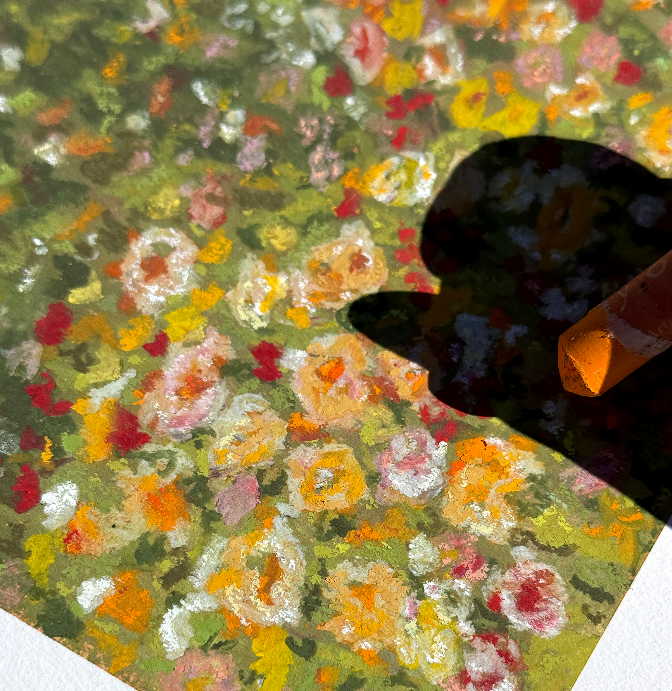 Close-up of a colorful abstract painting or print with various small, textured spots in green, yellow, orange, red, pink, black, and white. Part of a corner of a paper or canvas is visible with a curved edge and a brownish spot.
