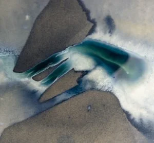 Close-up of a torn paper revealing a colorful abstract design underneath