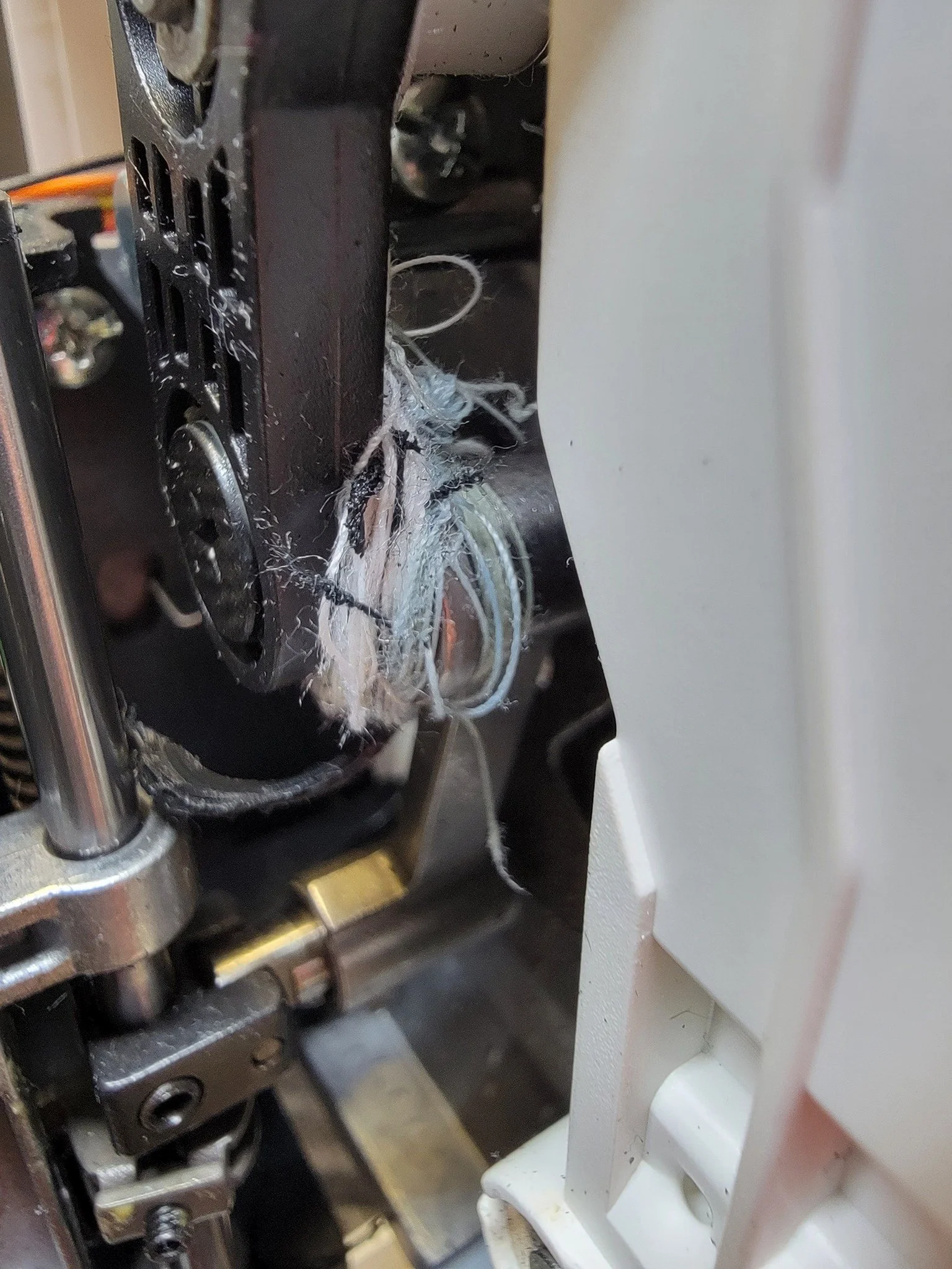 Close-up of a sewing machine with frayed  and broken threads.
