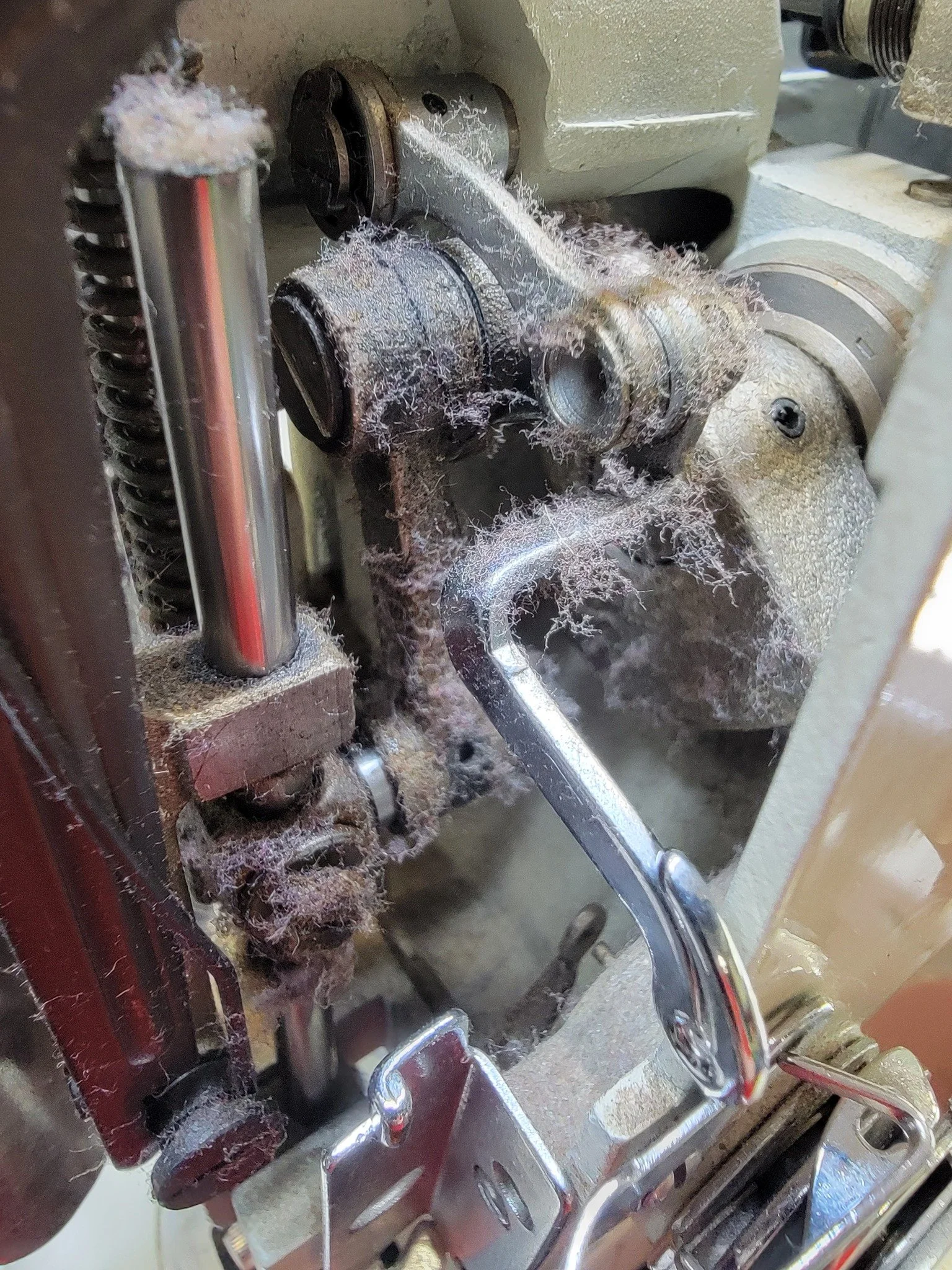 Close-up of a sewing machine, showing the build-up of dust and threads.