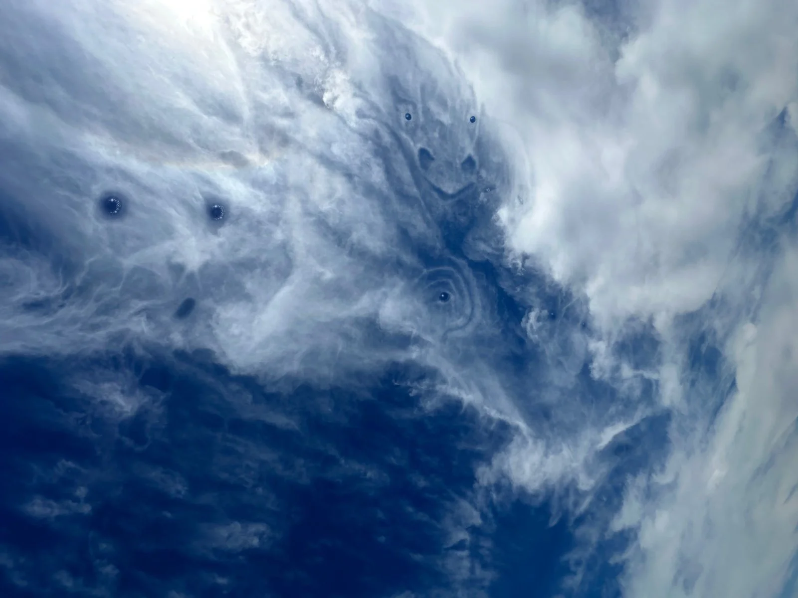Satellite image showing cloud formations and a large swirling storm system in the atmosphere.