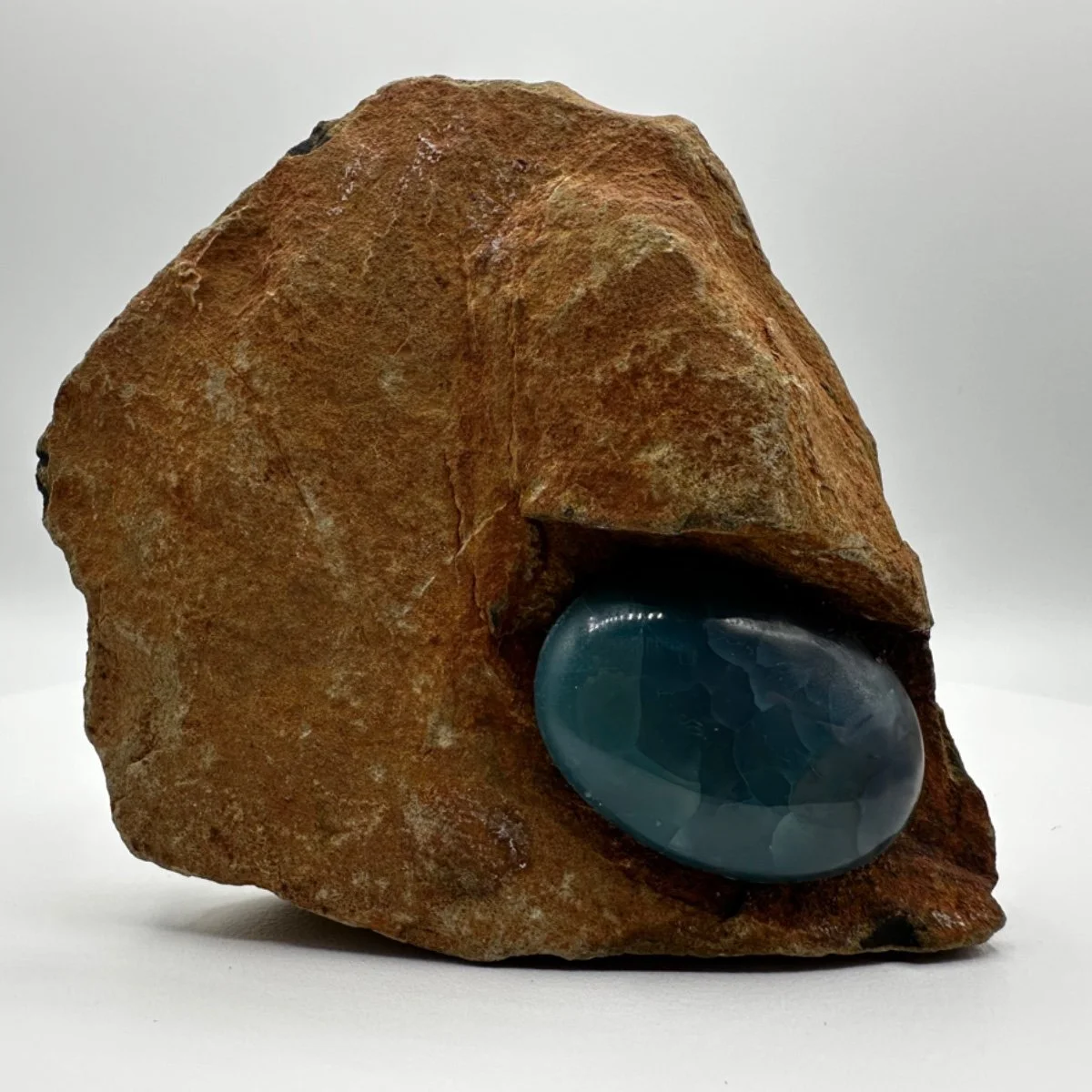 A large, rough, reddish-brown rock with a polished blue-gray stone embedded in it.