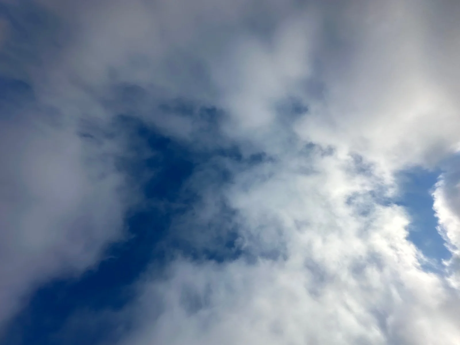 A view of the sky with scattered clouds and patches of blue.