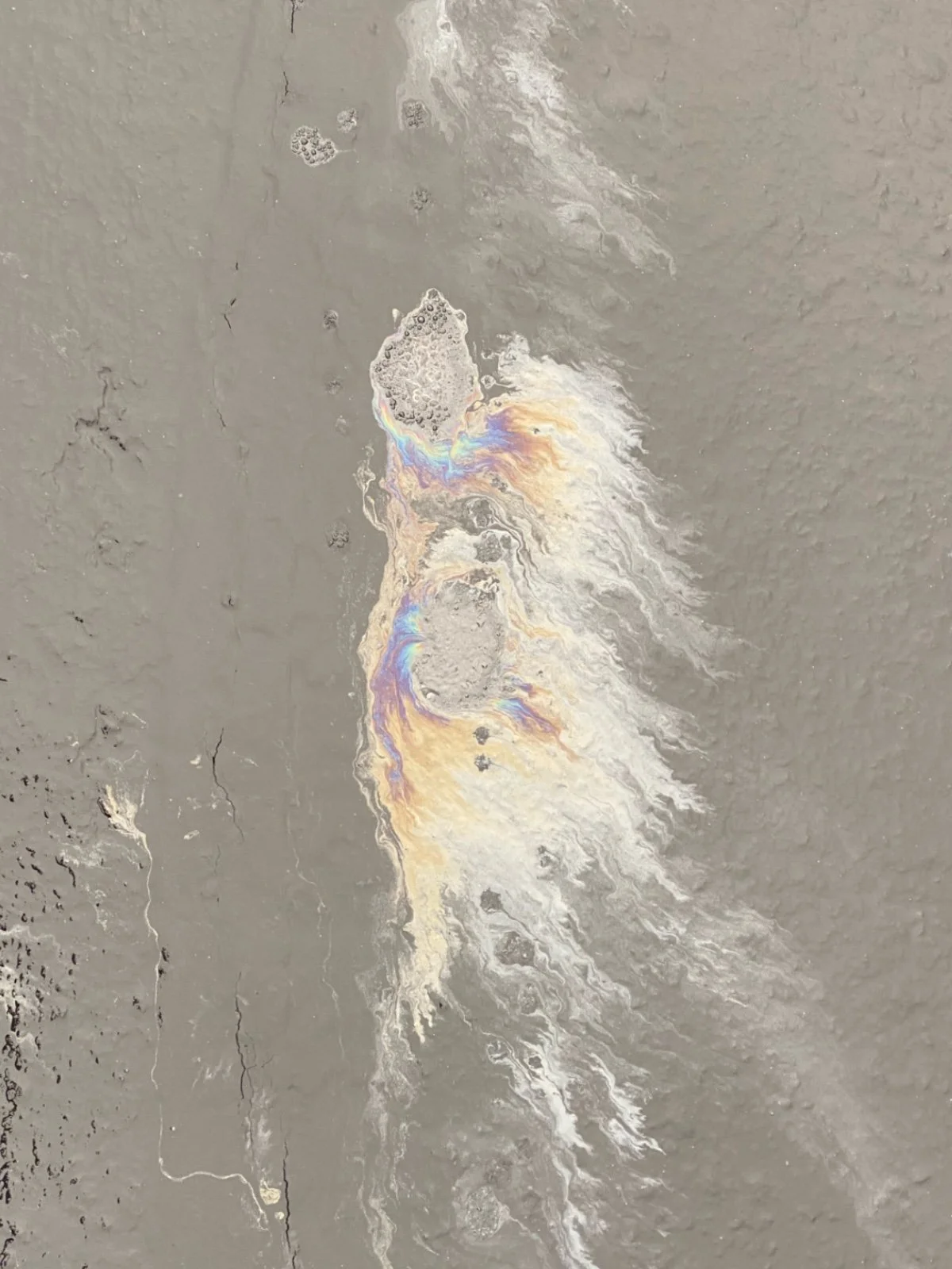 Close-up of a metallic surface with colorful oil slick patterns.