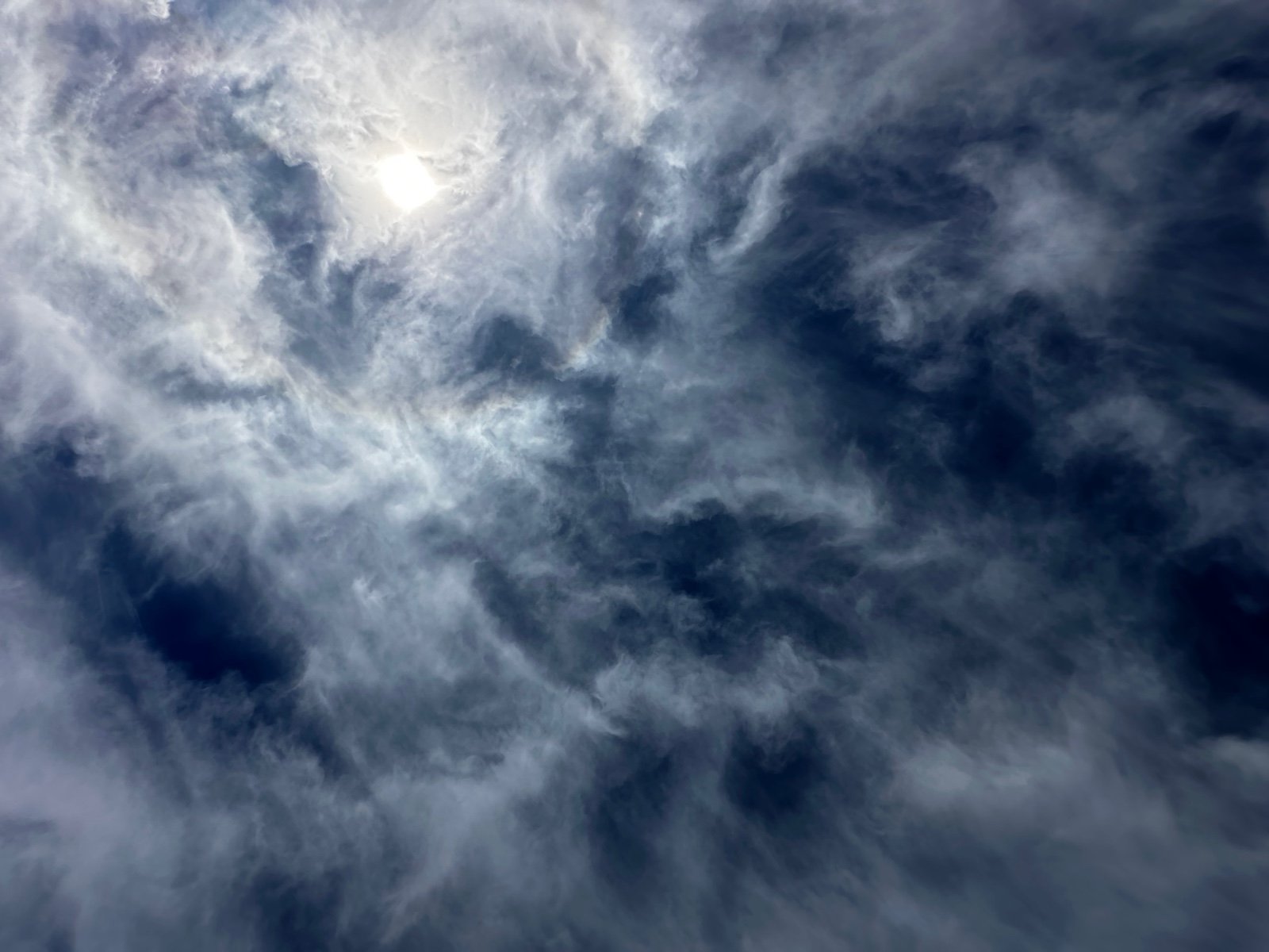 Sky with clouds and the sun partially visible through them.