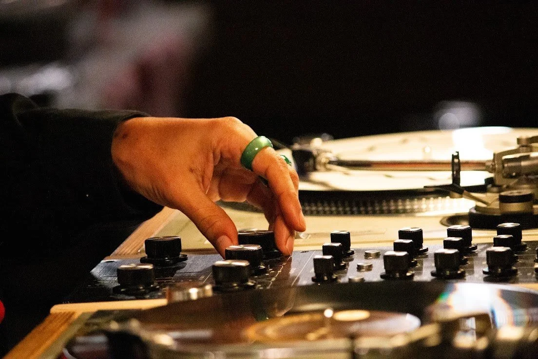 DJ mixing vinyl records during an event at Fort Worth Barbershop.