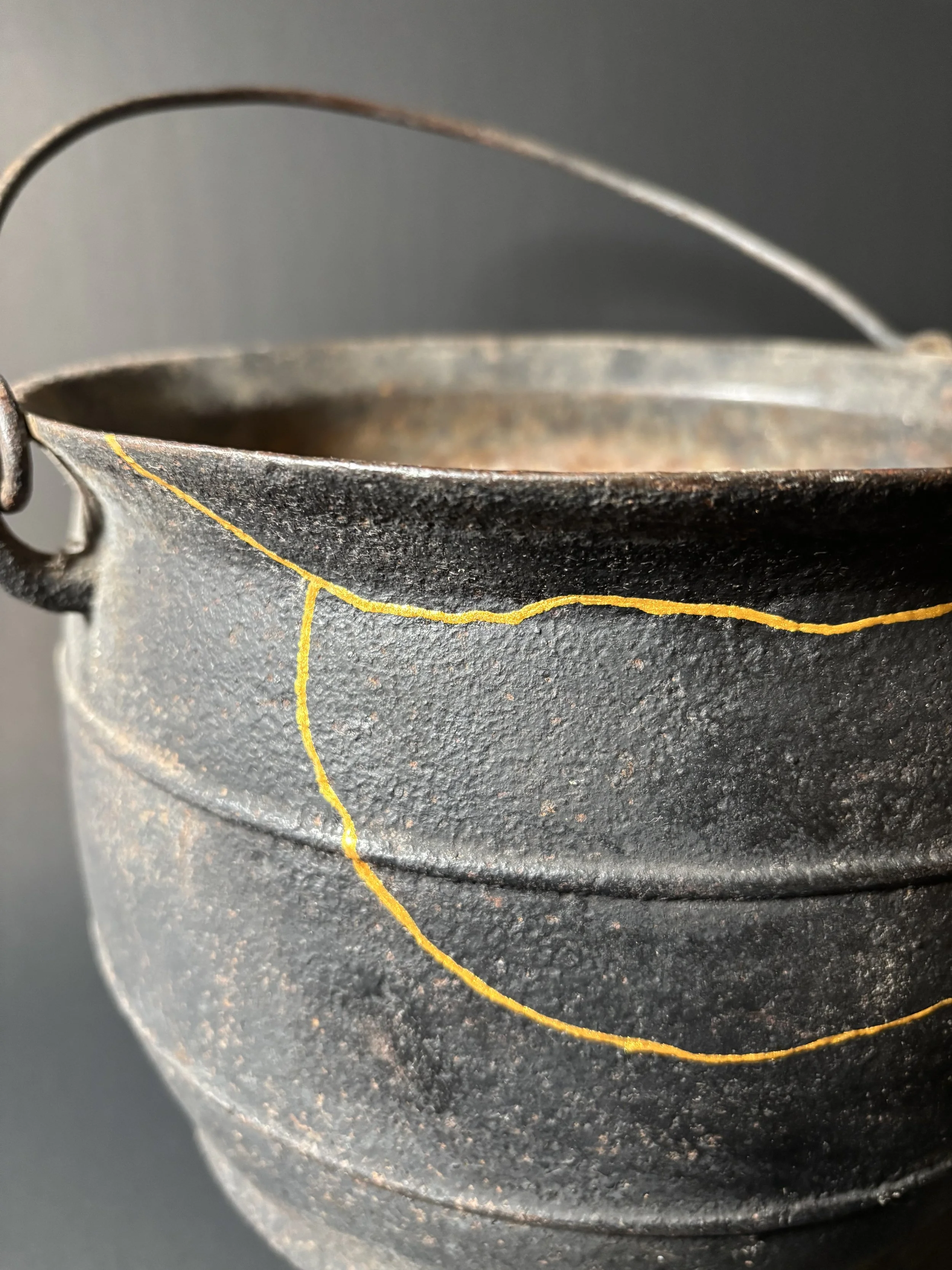 Close-up of a vintage cast iron pot with a yellow crackled paint design.