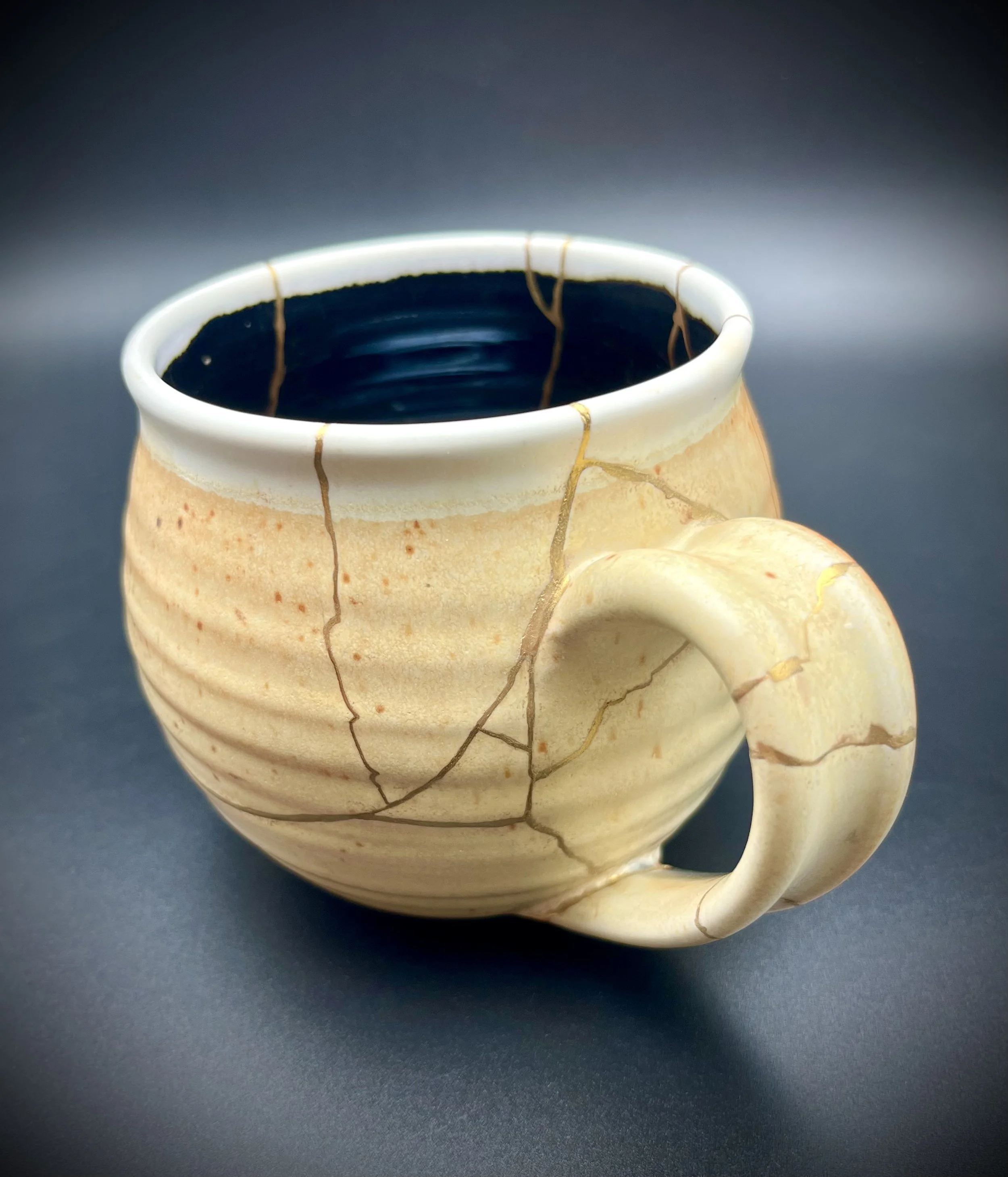 Close-up of a ceramic mug with a beige and light brown marbled pattern, filled with black coffee, against a dark background.
