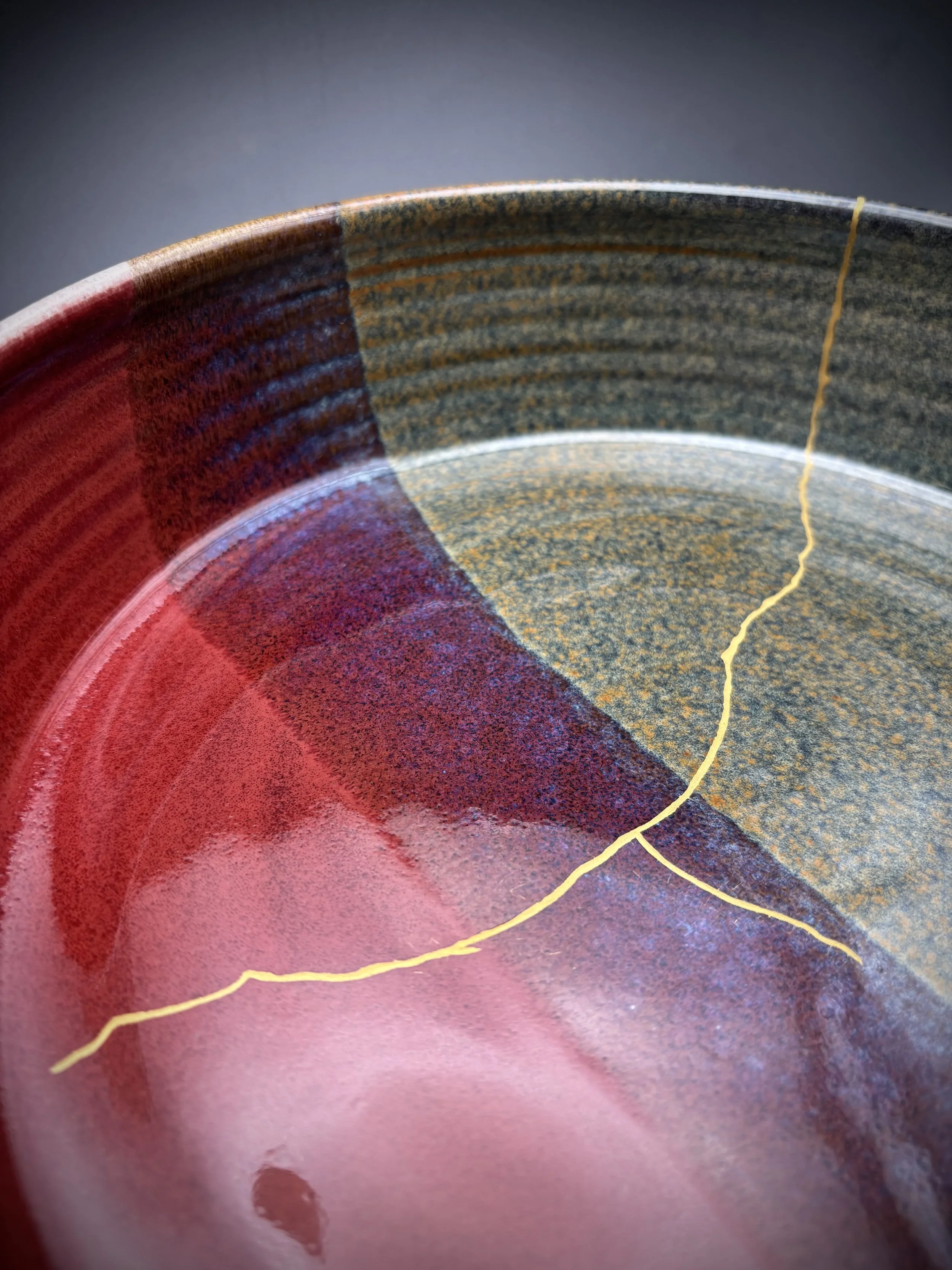 Close-up of a ceramic bowl with a textured, multicolored glaze, featuring a crack running through the interior.