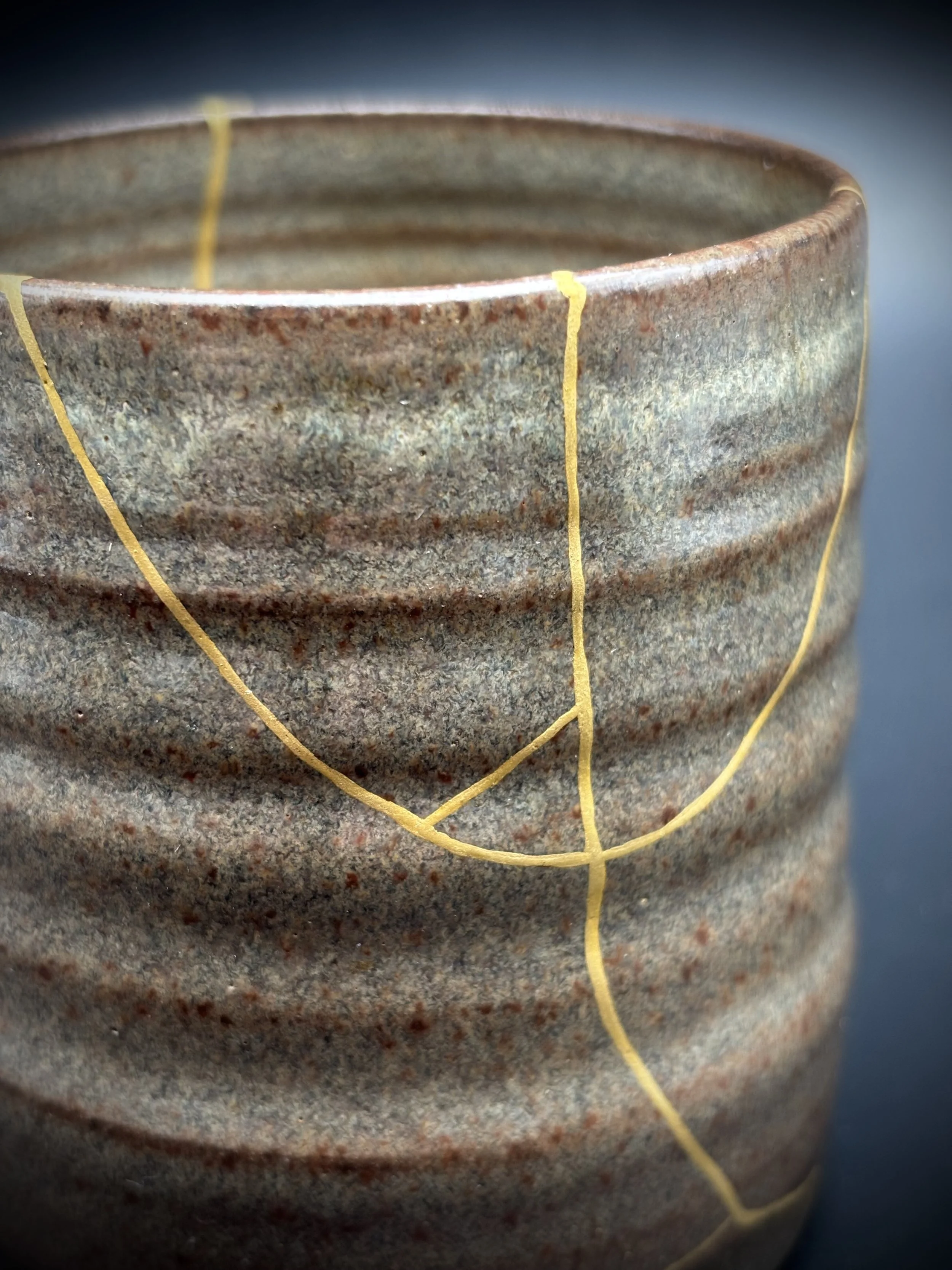 Close-up of a rustic ceramic bowl with a textured, speckled surface, wrapped with thin yellow thread.