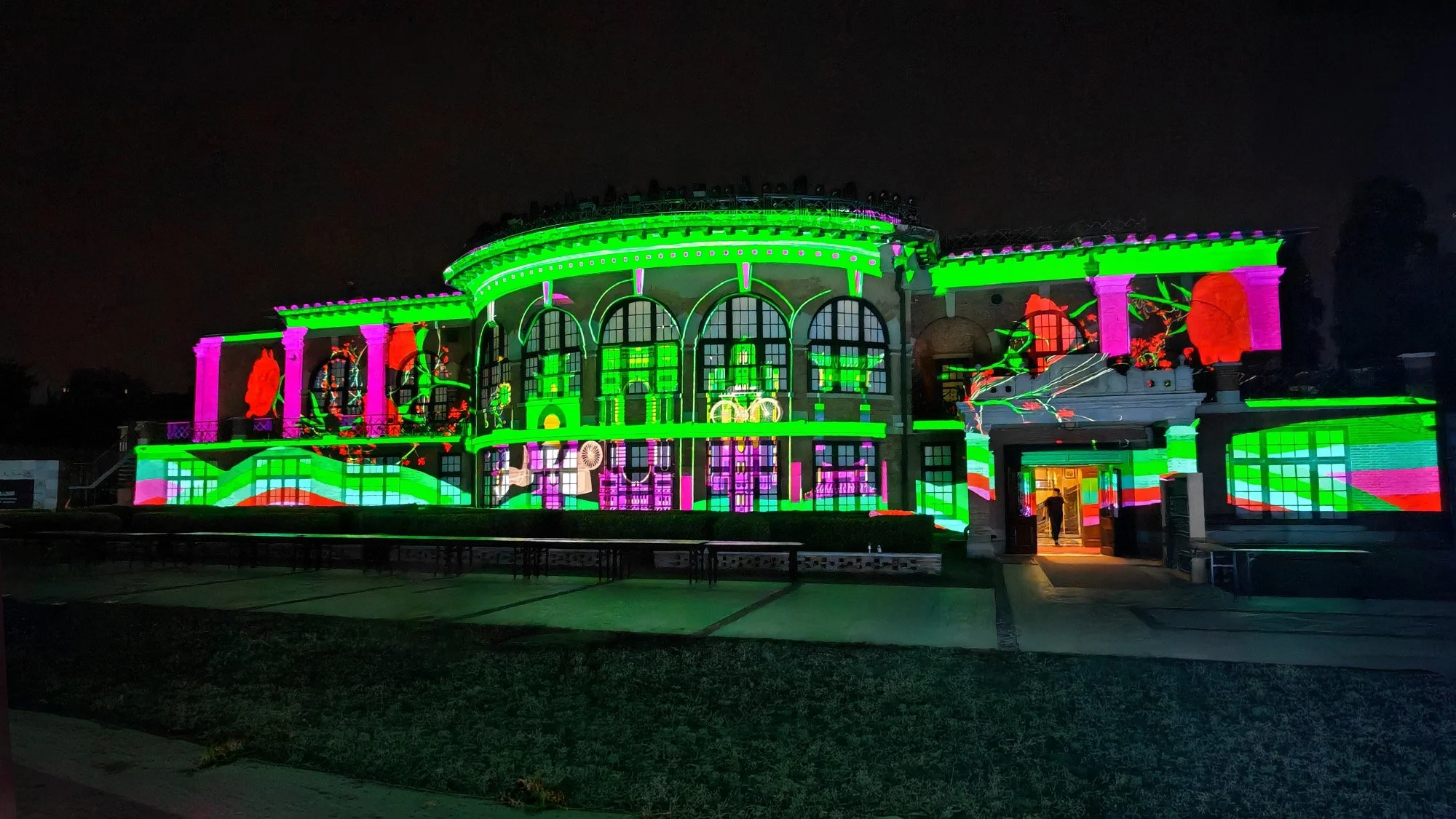 Light show at 2025 Davos Forum: Historic building with arched windows illuminated in green, pink, and purple lights.