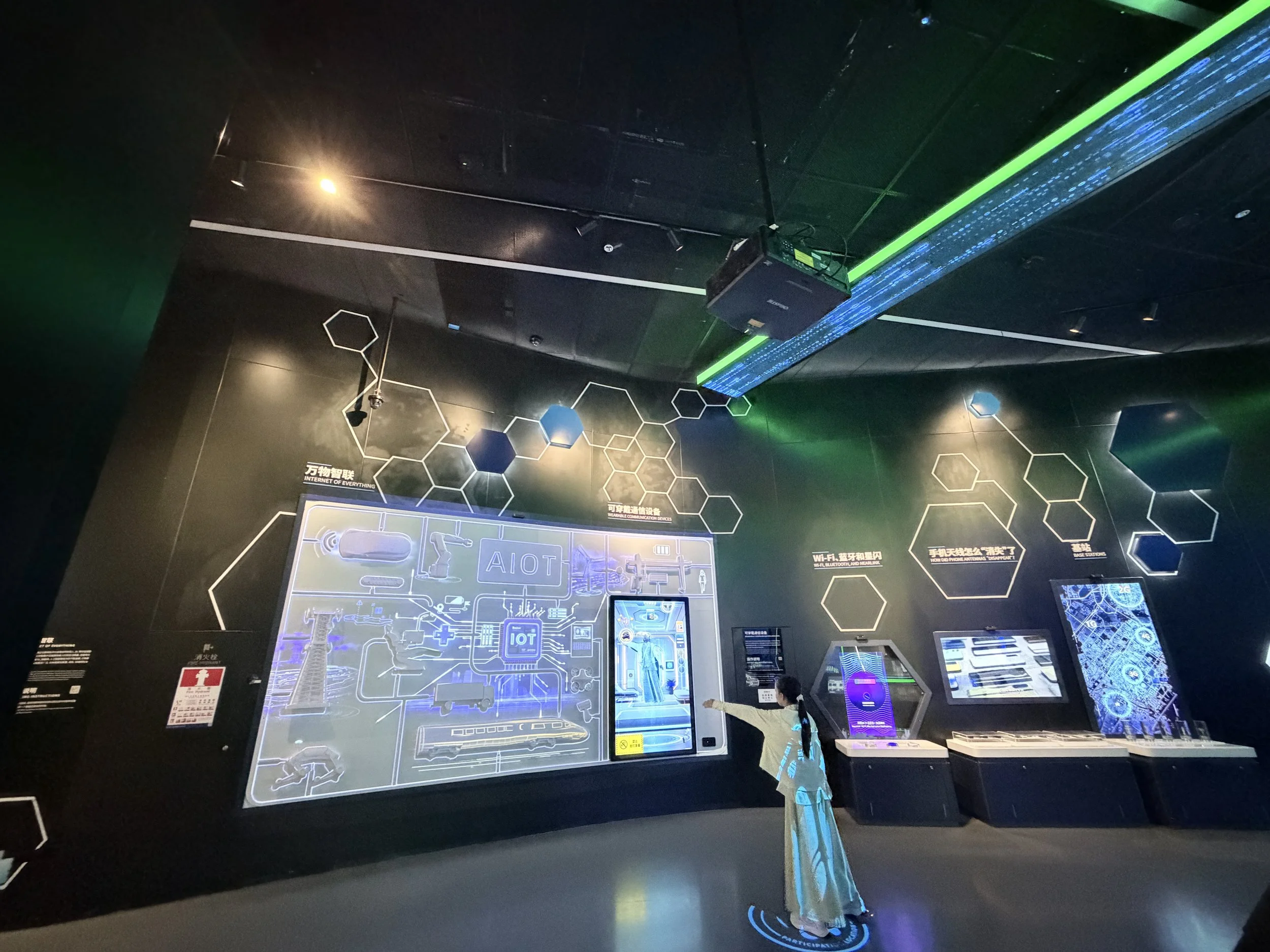 An interactive exhibit about the Internet of Everything, featuring digital diagrams and futuristic designs, with a young girl pointing at the display.-at a Shenzhen science or technology museum
