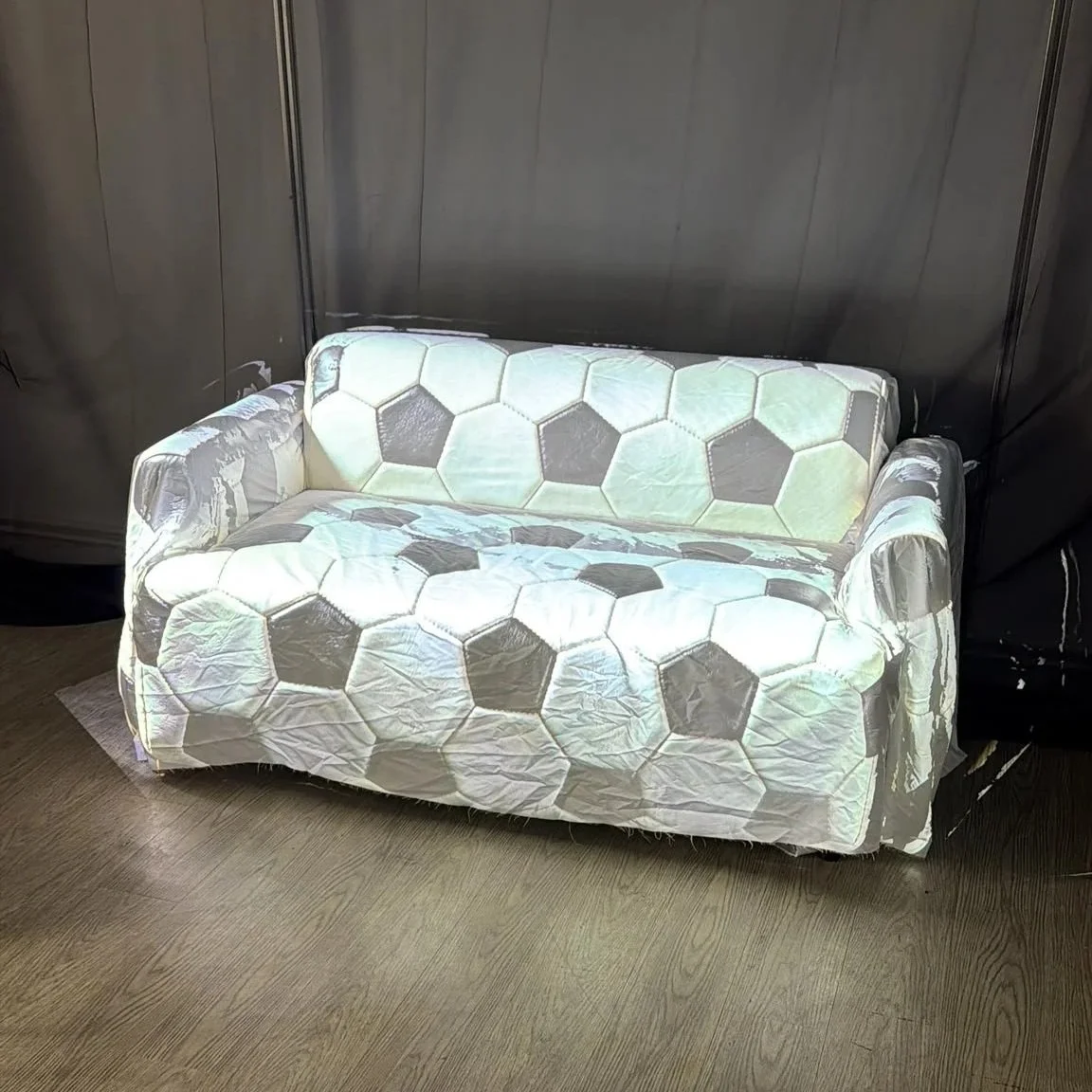 Ai Mapper software demo: Black-and-white soccer pattern projected onto a white small sofa in a dark room.