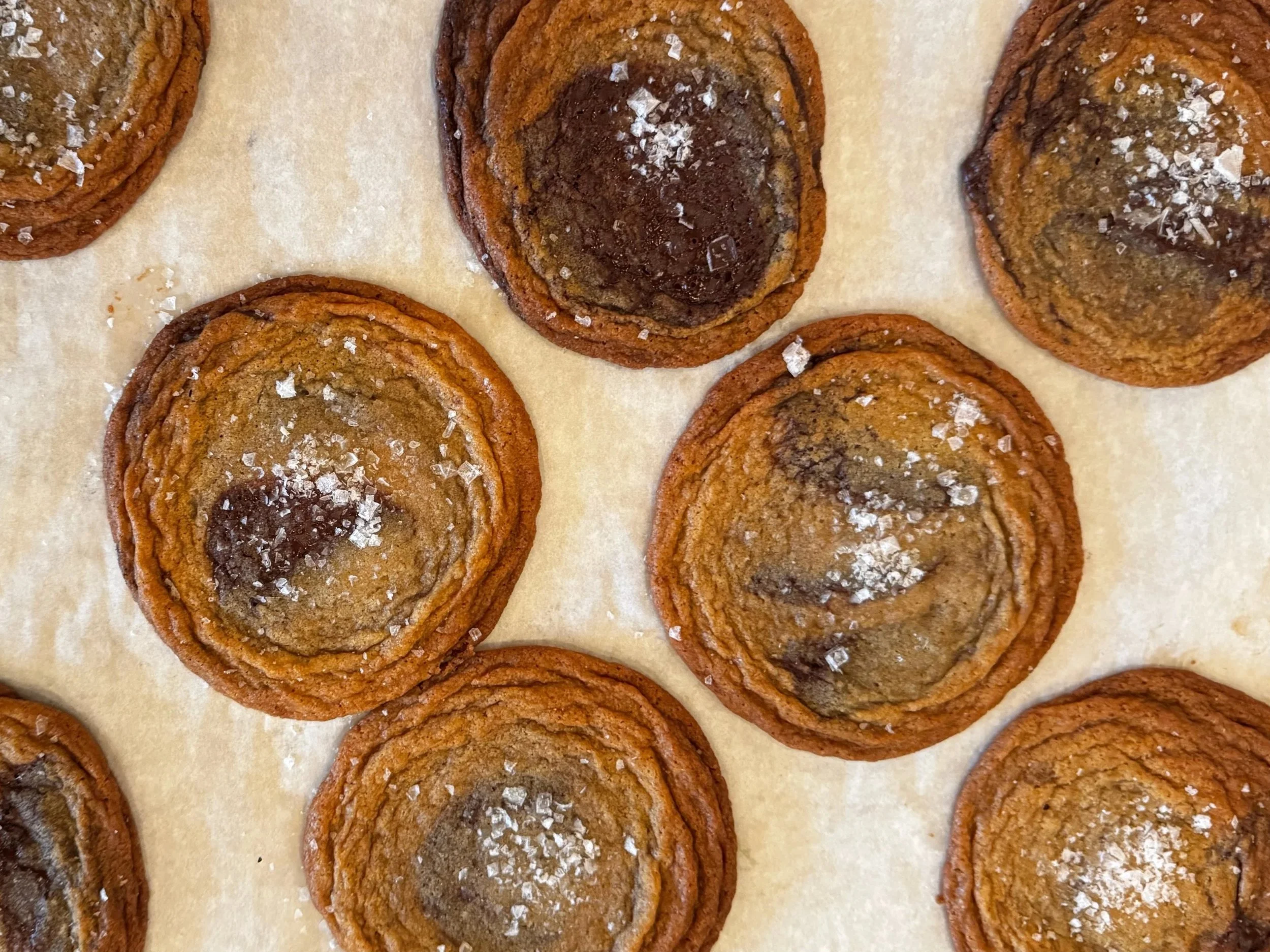 Chocolate babka slices with swirled dough, topped with coarse sea salt on parchment paper.
