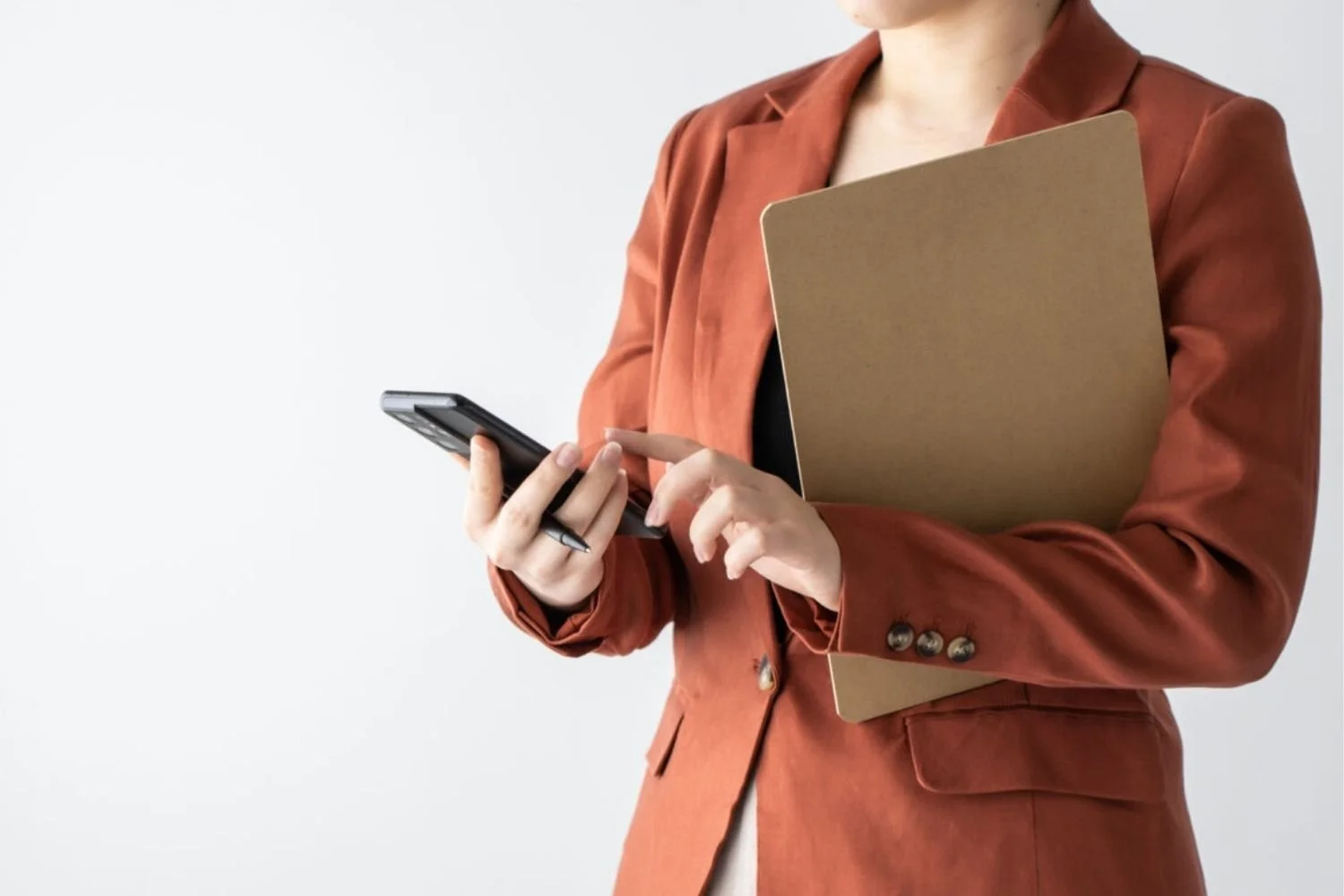 Professional holding a folder and phone, representing employer brand strategy and workplace coaching support.