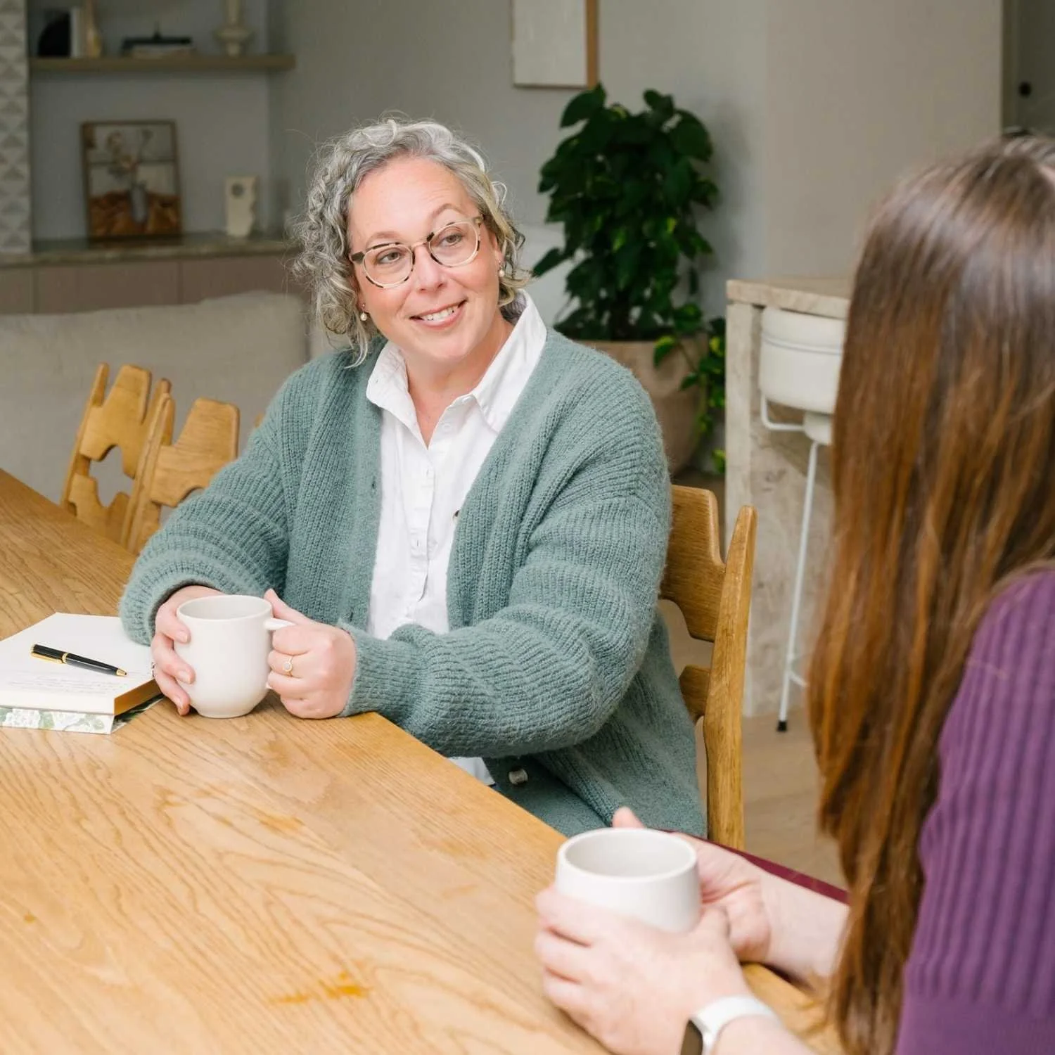 Hannah from Small Circle having a career coaching conversation with a client at a table in a relaxed professional setting.